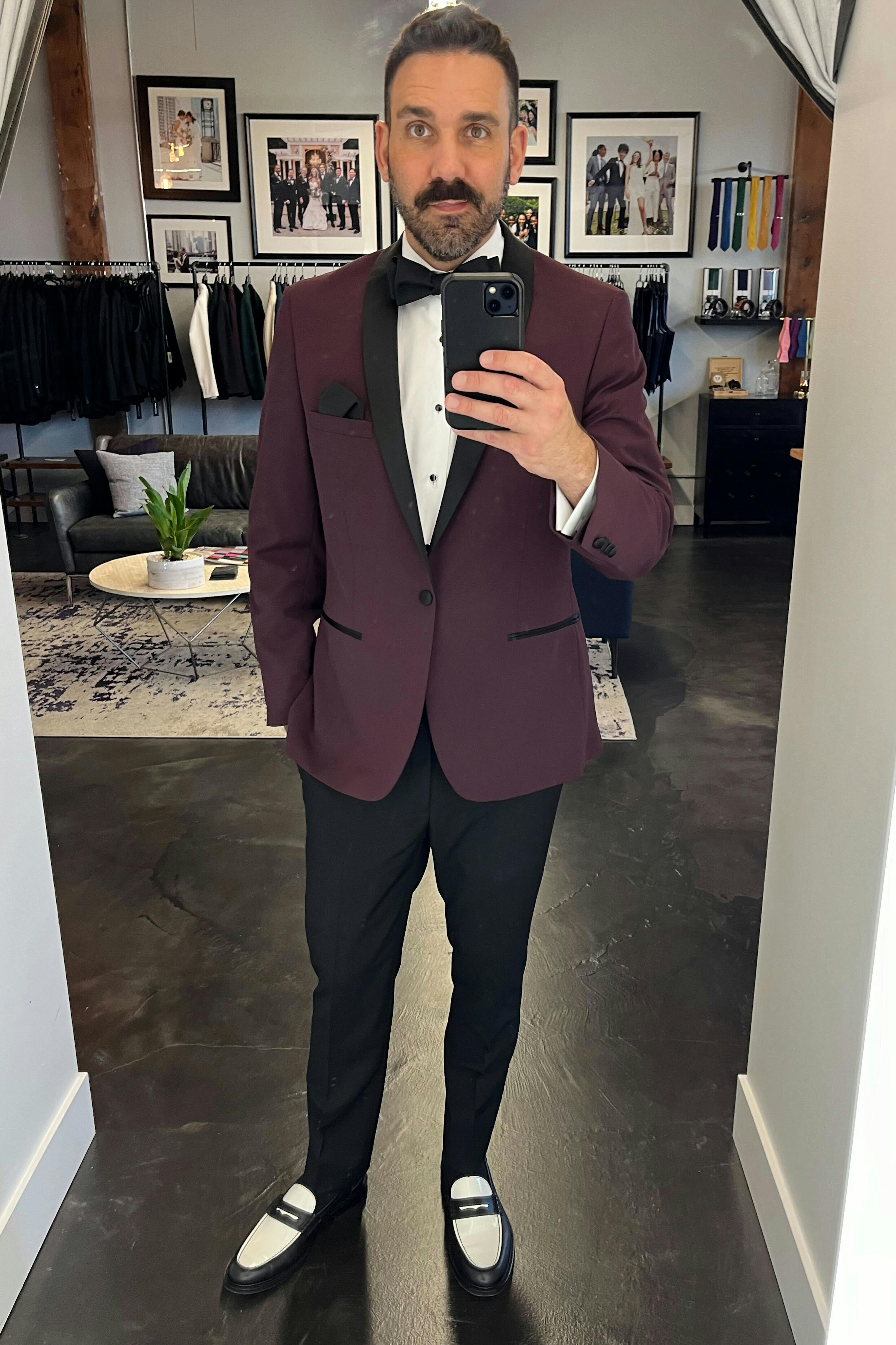 Posing in mirror wearing men's burgundy shawl lapel tuxedo