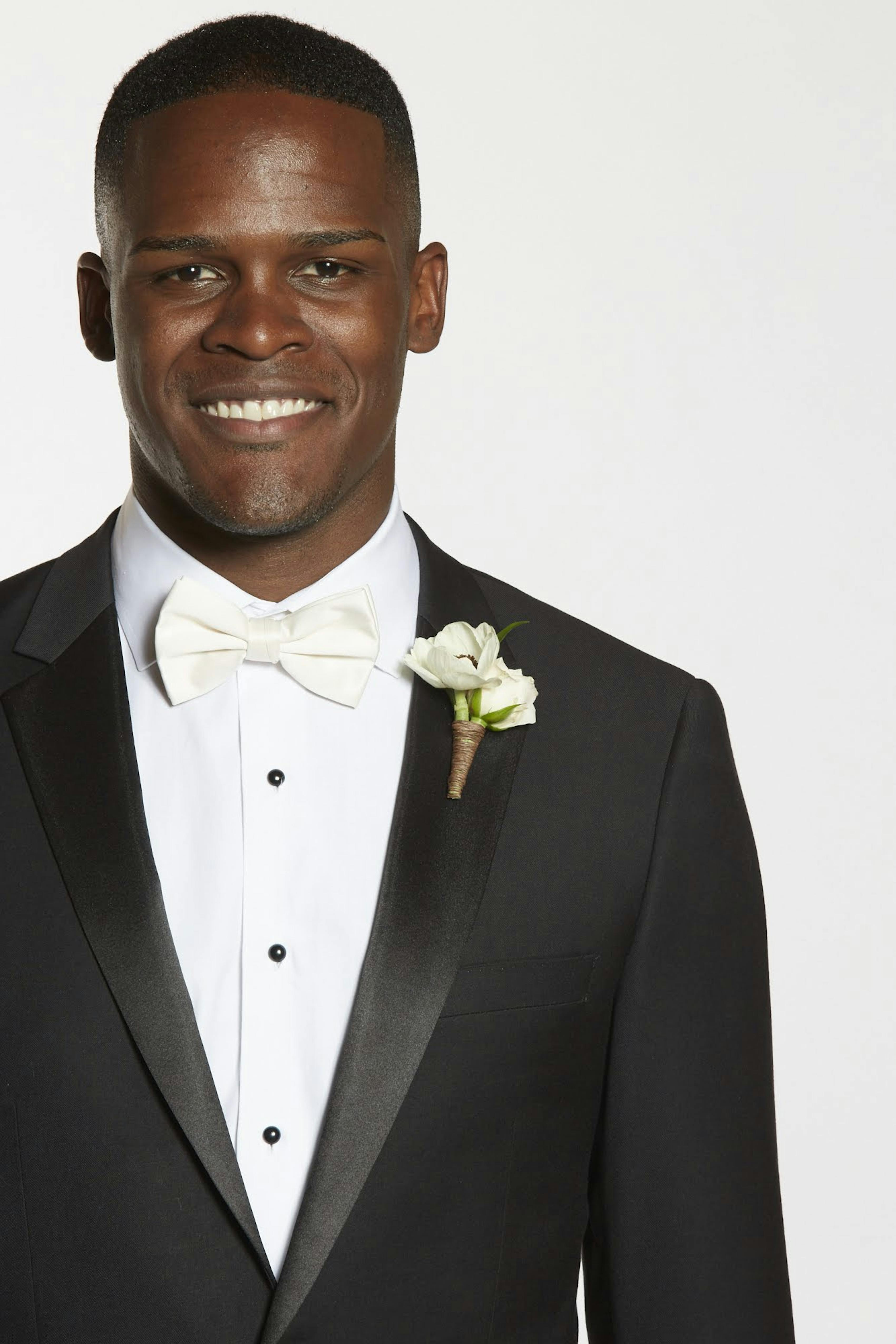 Men's white tie attire with black peak lapel tuxedo, stud tuxedo shirt, white bow tie, and boutonniere.