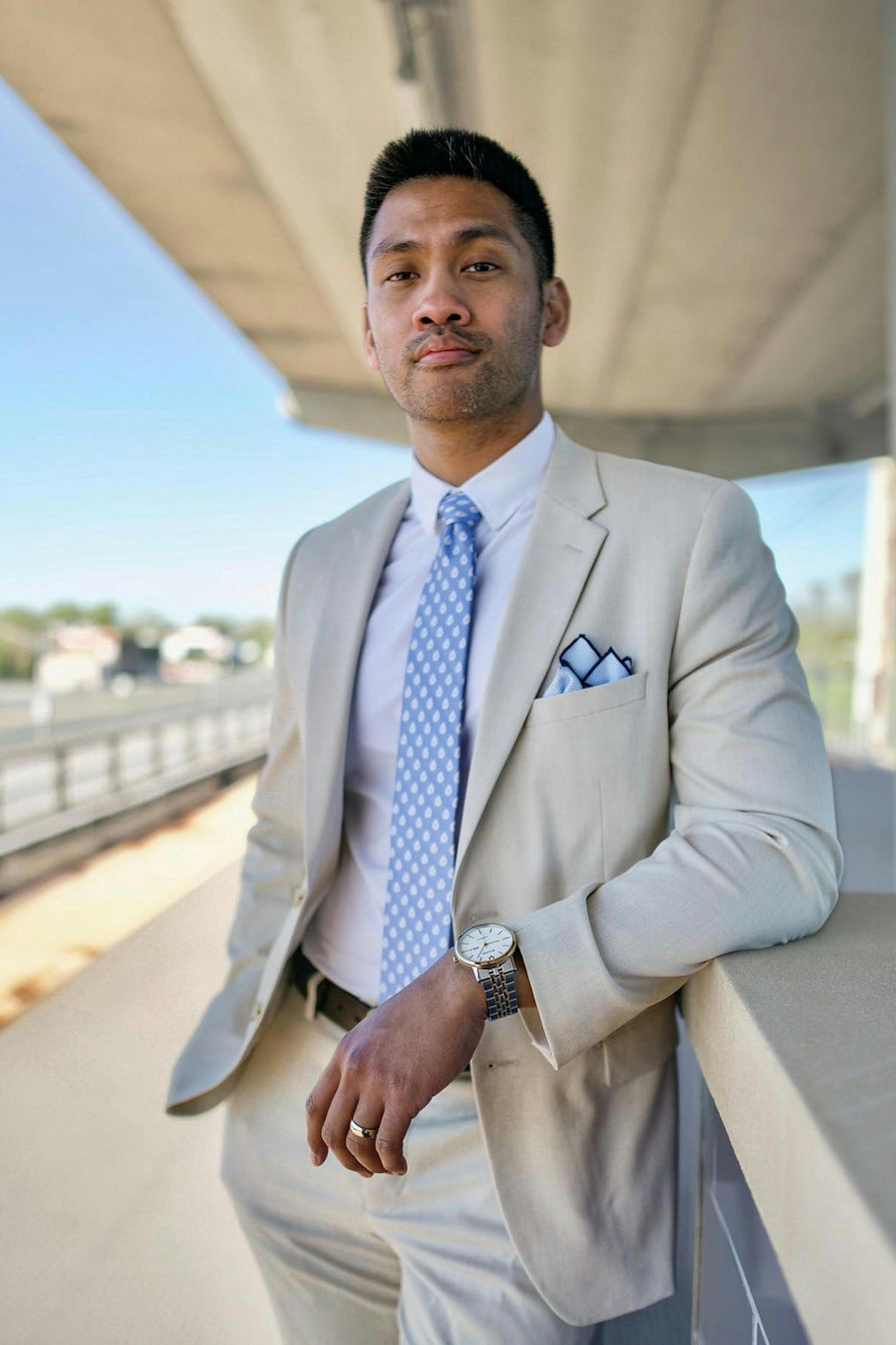 Light tan men's suit with light blue tie and pocket square showing how to accessorize for summer wedding