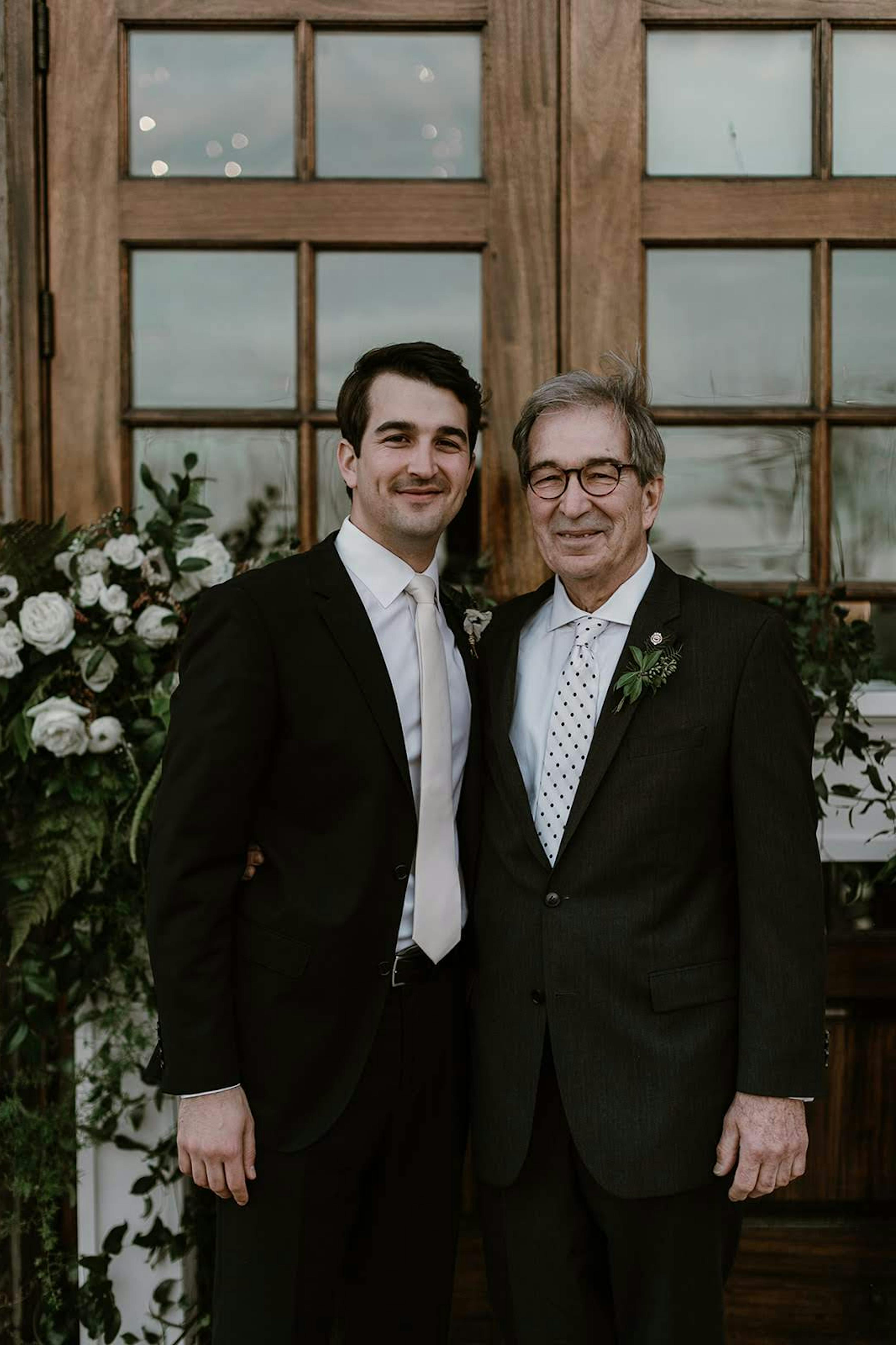 Groom and father of the groom in black wedding suits with different ties