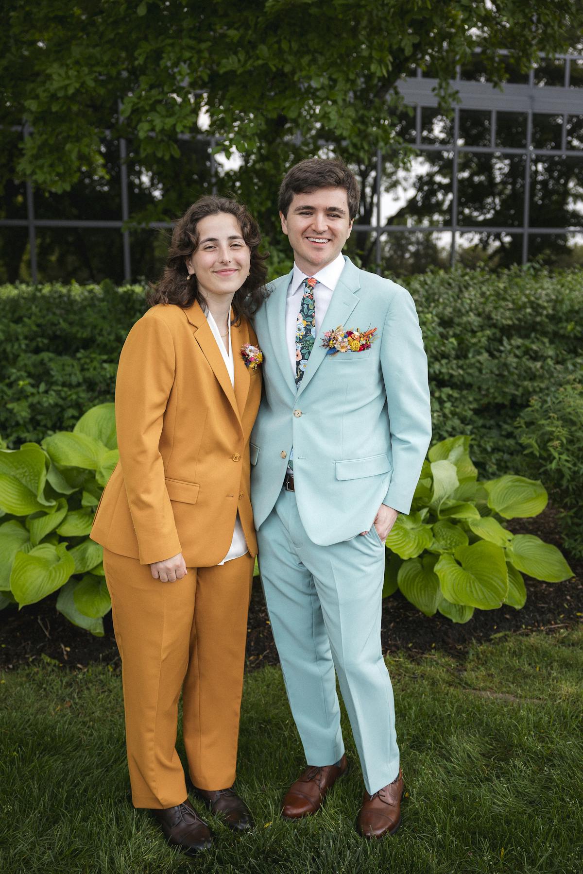 Colorful suits for outdoor event with man in pastel blue suit and woman in orange suit