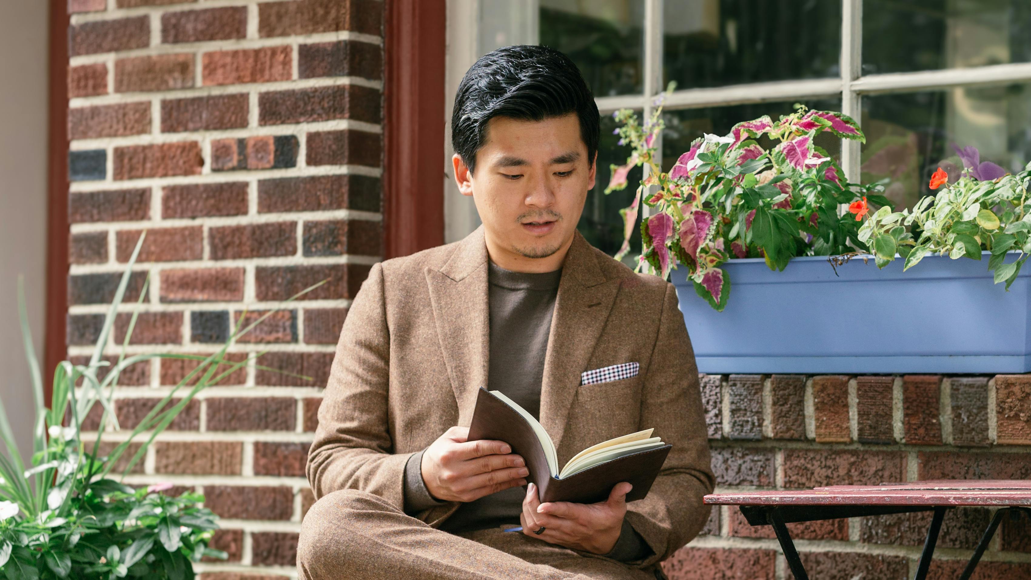 Man wearing tweed suit, patterned pocket square, and brown sweater for everyday fall outfit.