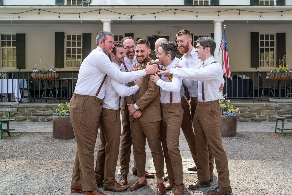 Wedding group of groomsmen wearing tweed suits with suspenders and brown dress shoes.