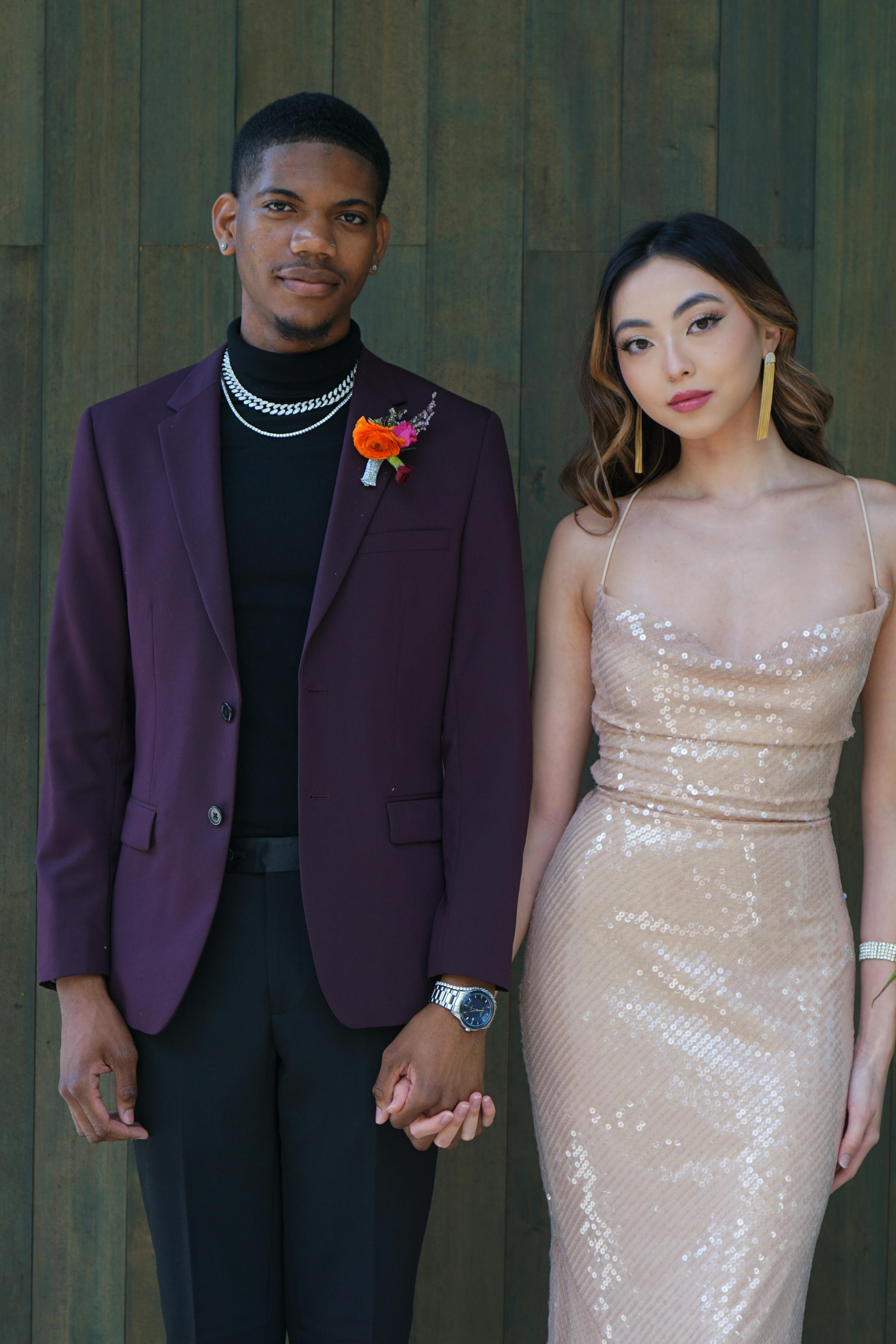 Formal wedding guest outfits for fall with burgundy suit jacket, black suit pants, and champagne dress.