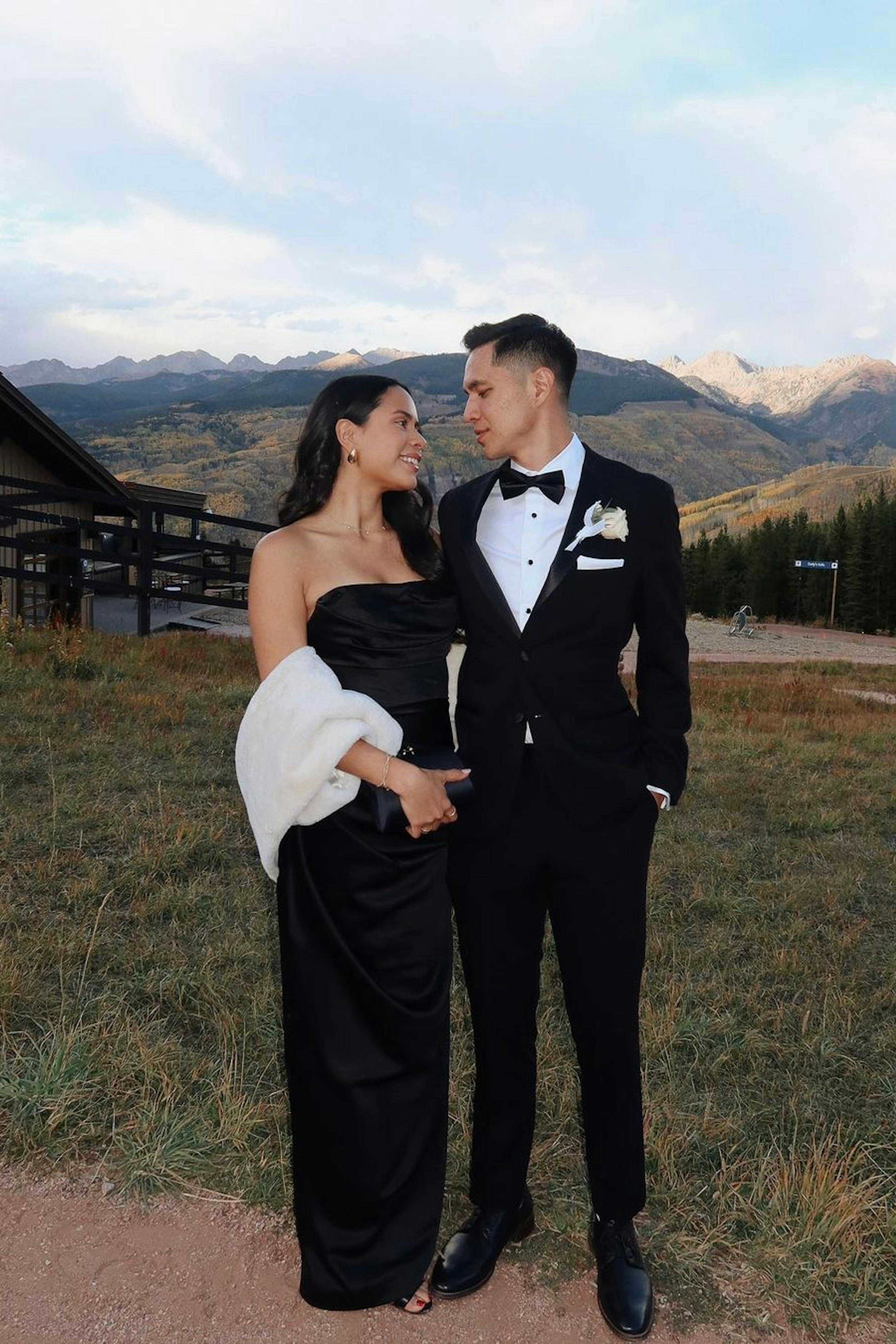 Man and woman at outdoor mountain wedding in fall wearing black tuxedo, gown, and fur shawl.
