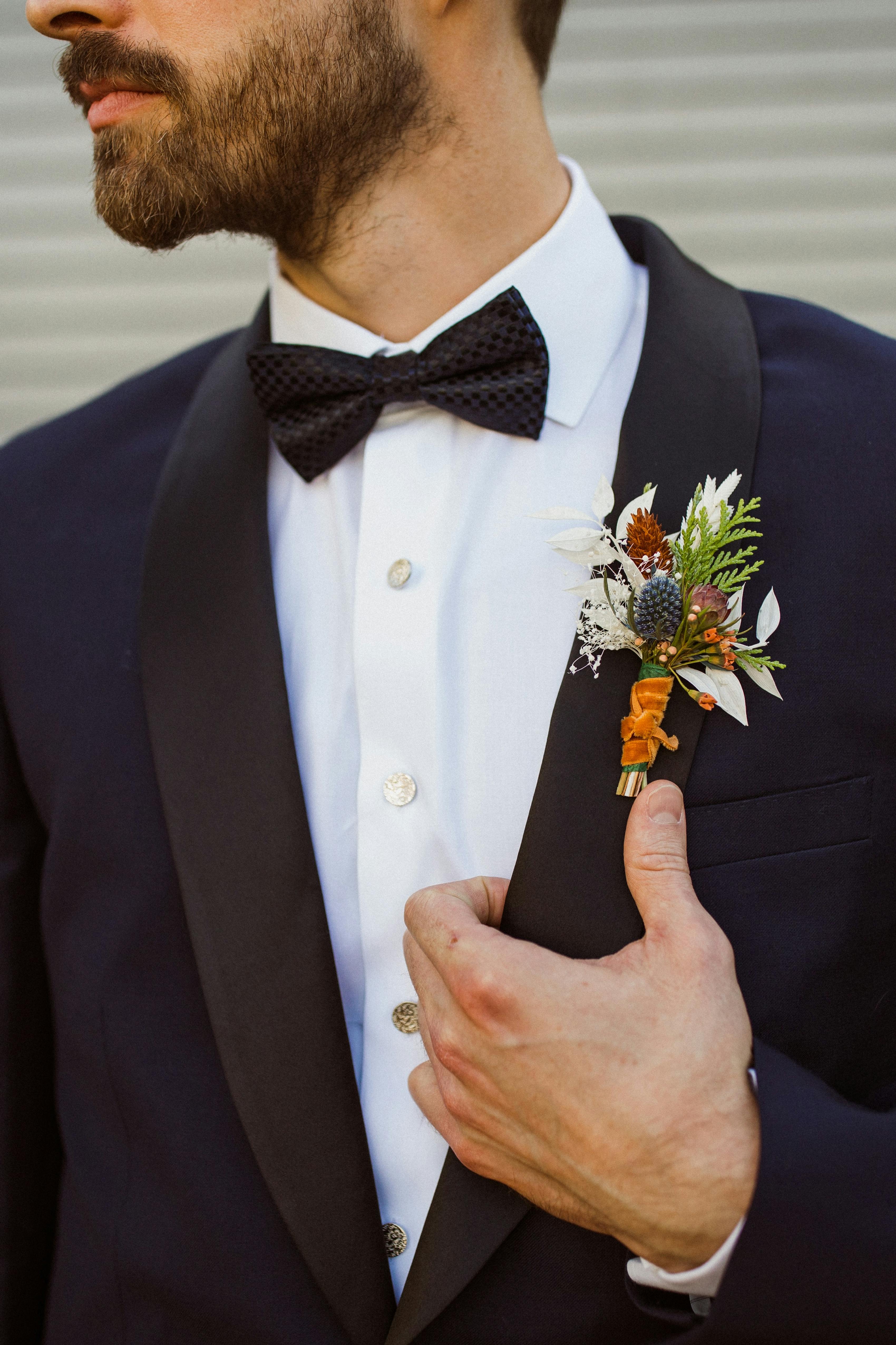 Men's navy tuxedo with autumn boutonnière for fall wedding.