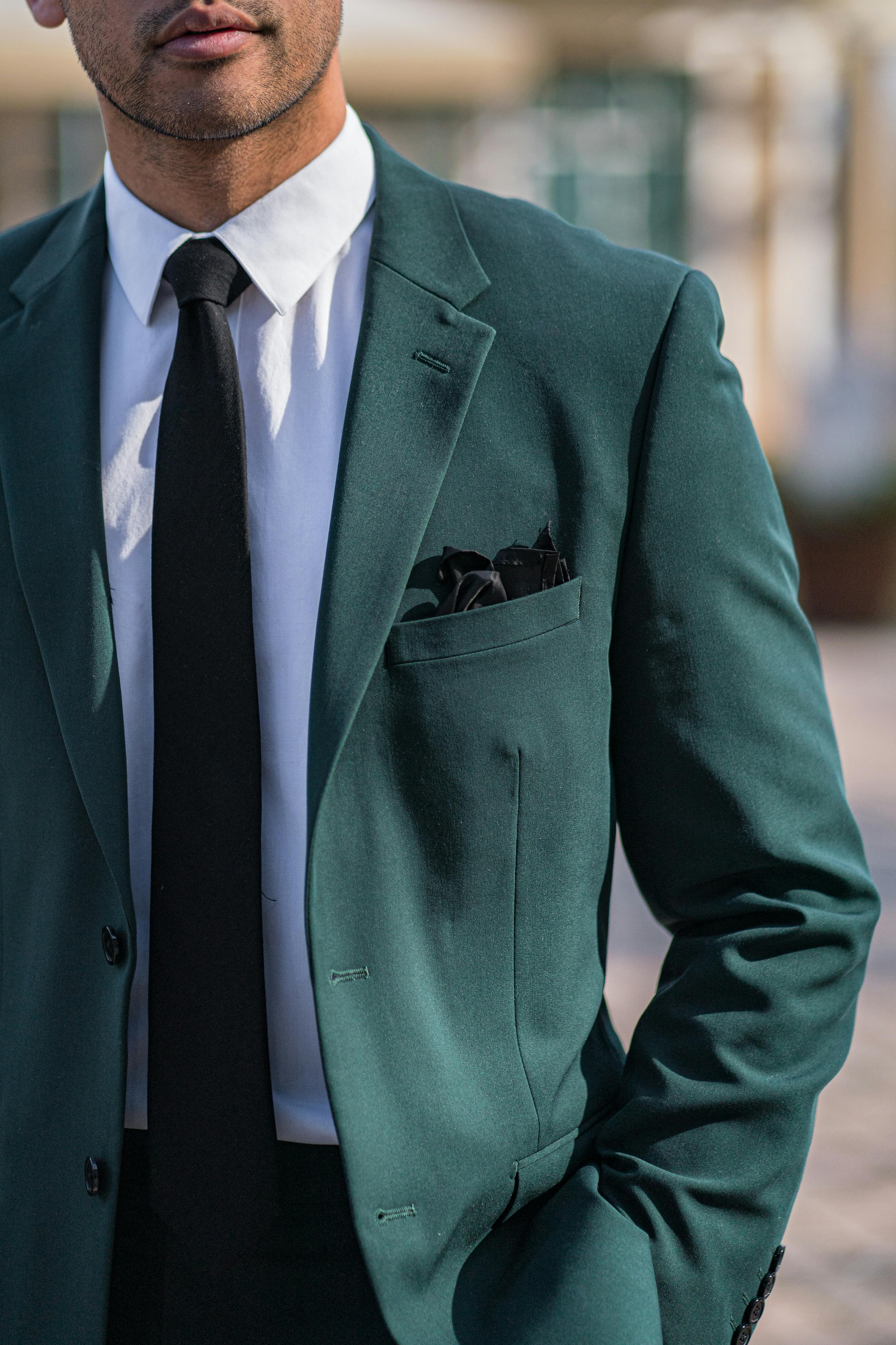 Men's fall wedding outfit colors with a dark green suit and black tie.