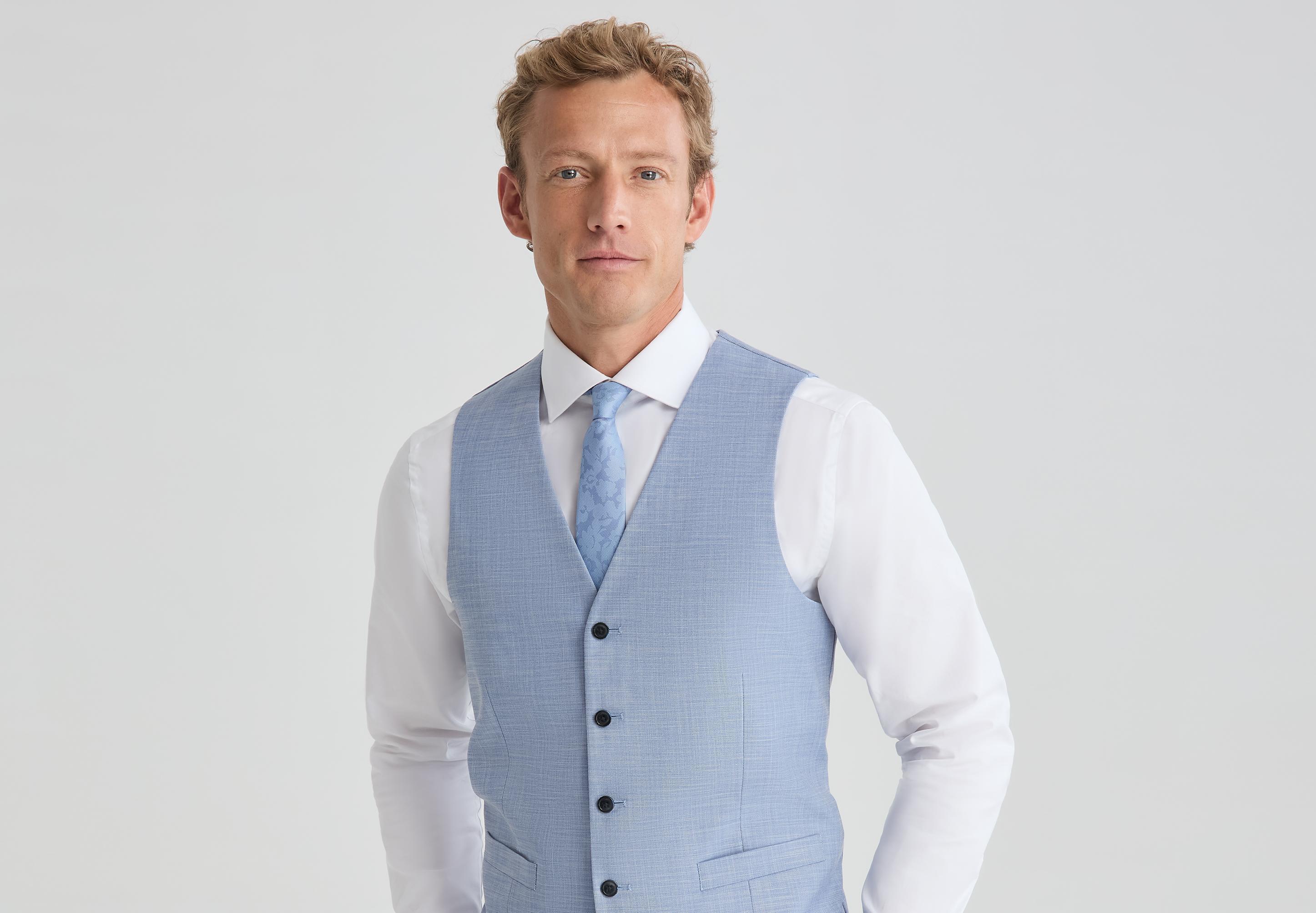 Man wearing a light blue vest with a white dress shirt and matching blue tie.