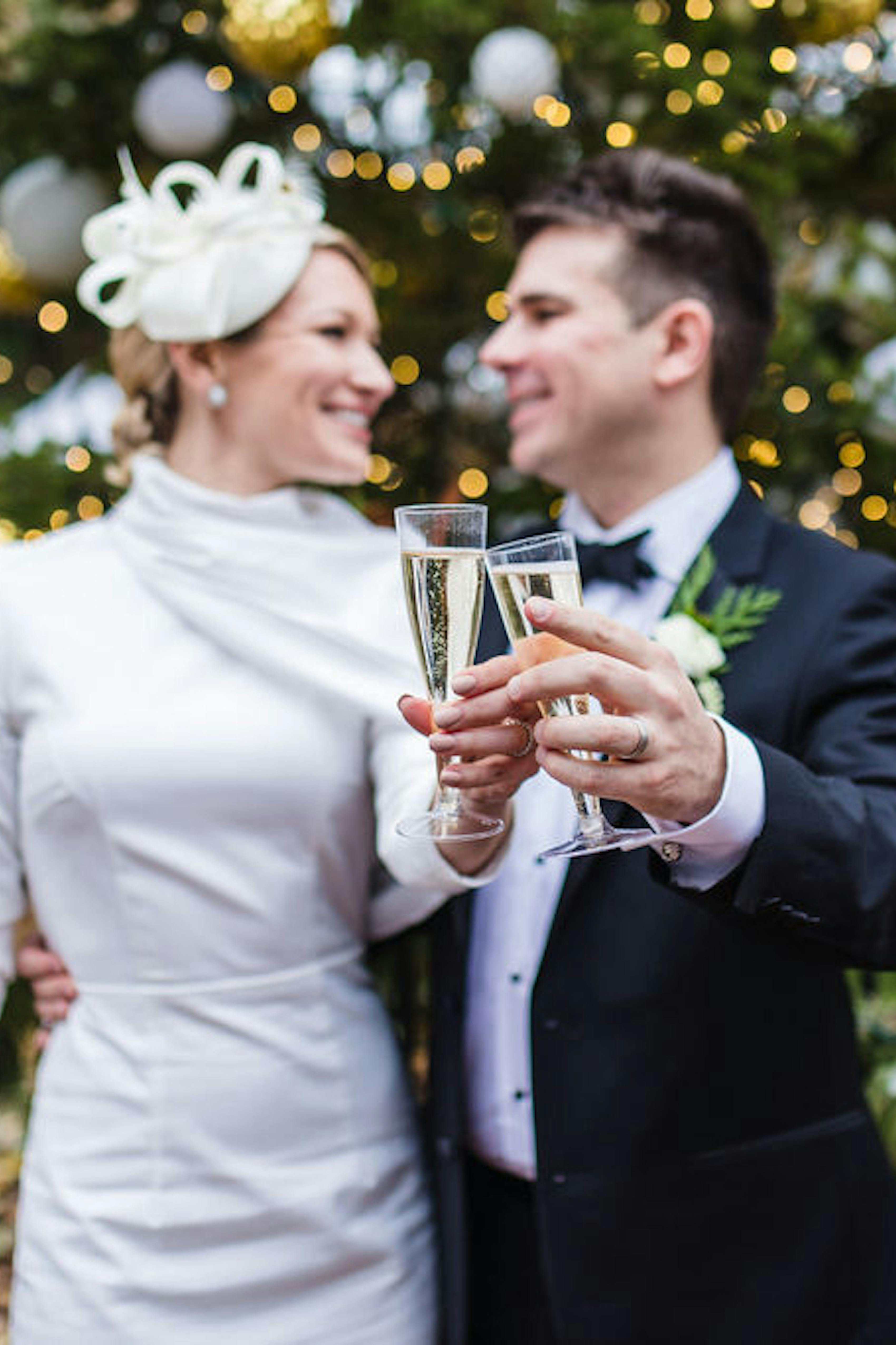 Festive couple posed in front of a Christmas tree, wearing holiday-ready attire.
