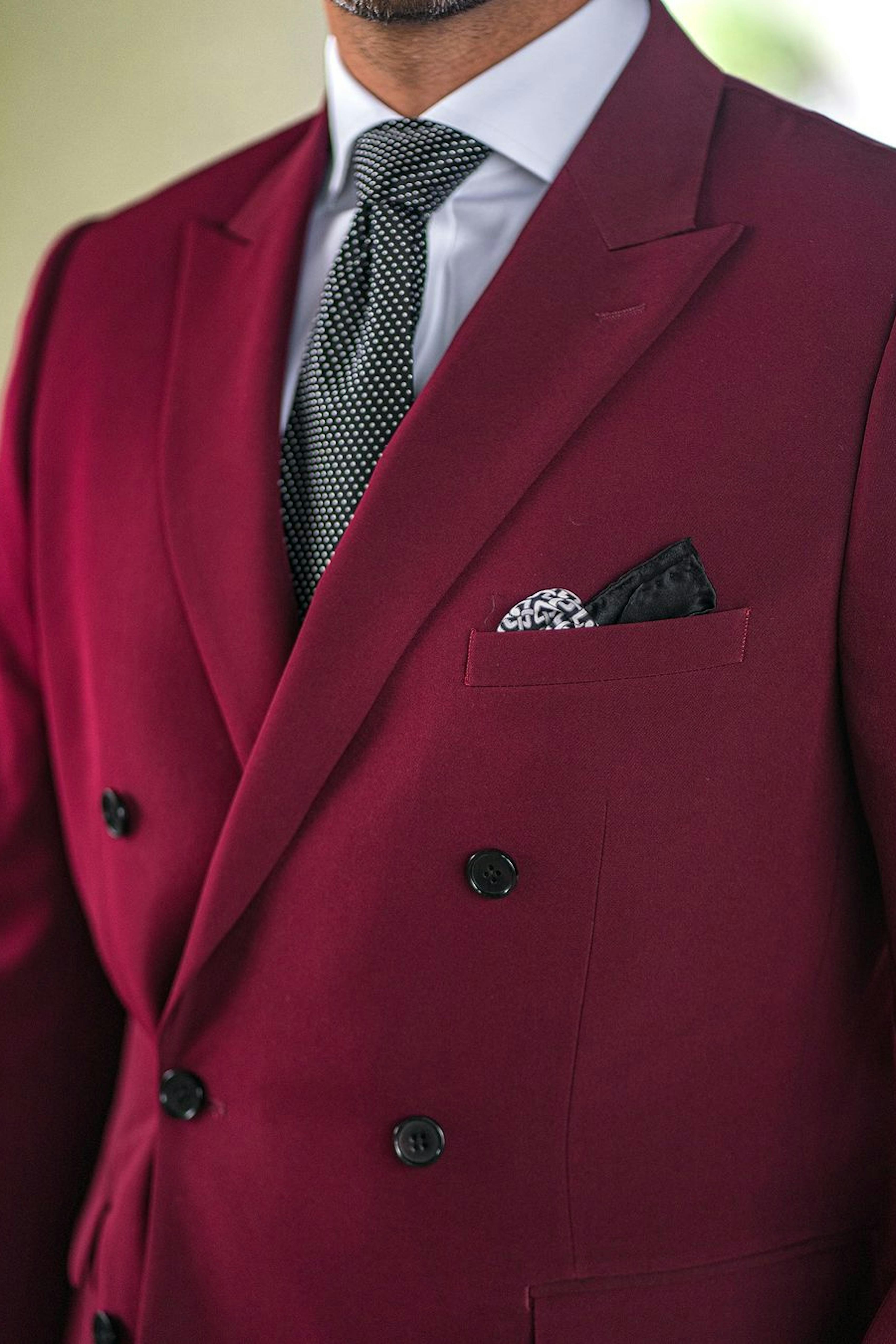 Holiday party-ready in a merlot double breasted suit jacket for men, styled with a black polkadot necktie