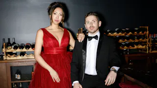 Couple dressed for formal Christmas party in red dress with ruffles and classic black tuxedo