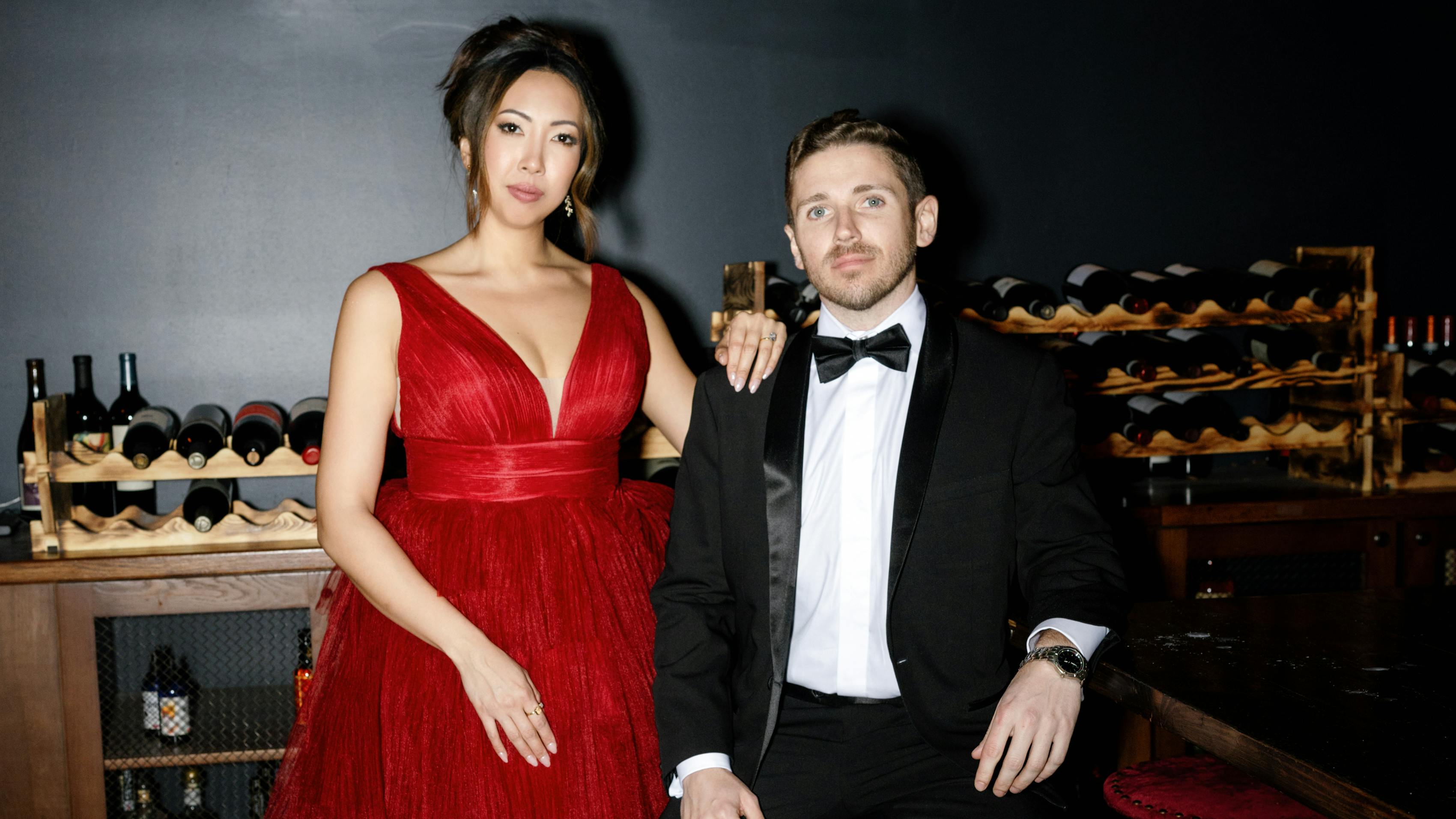 Couple dressed for formal Christmas party in red dress with ruffles and classic black tuxedo