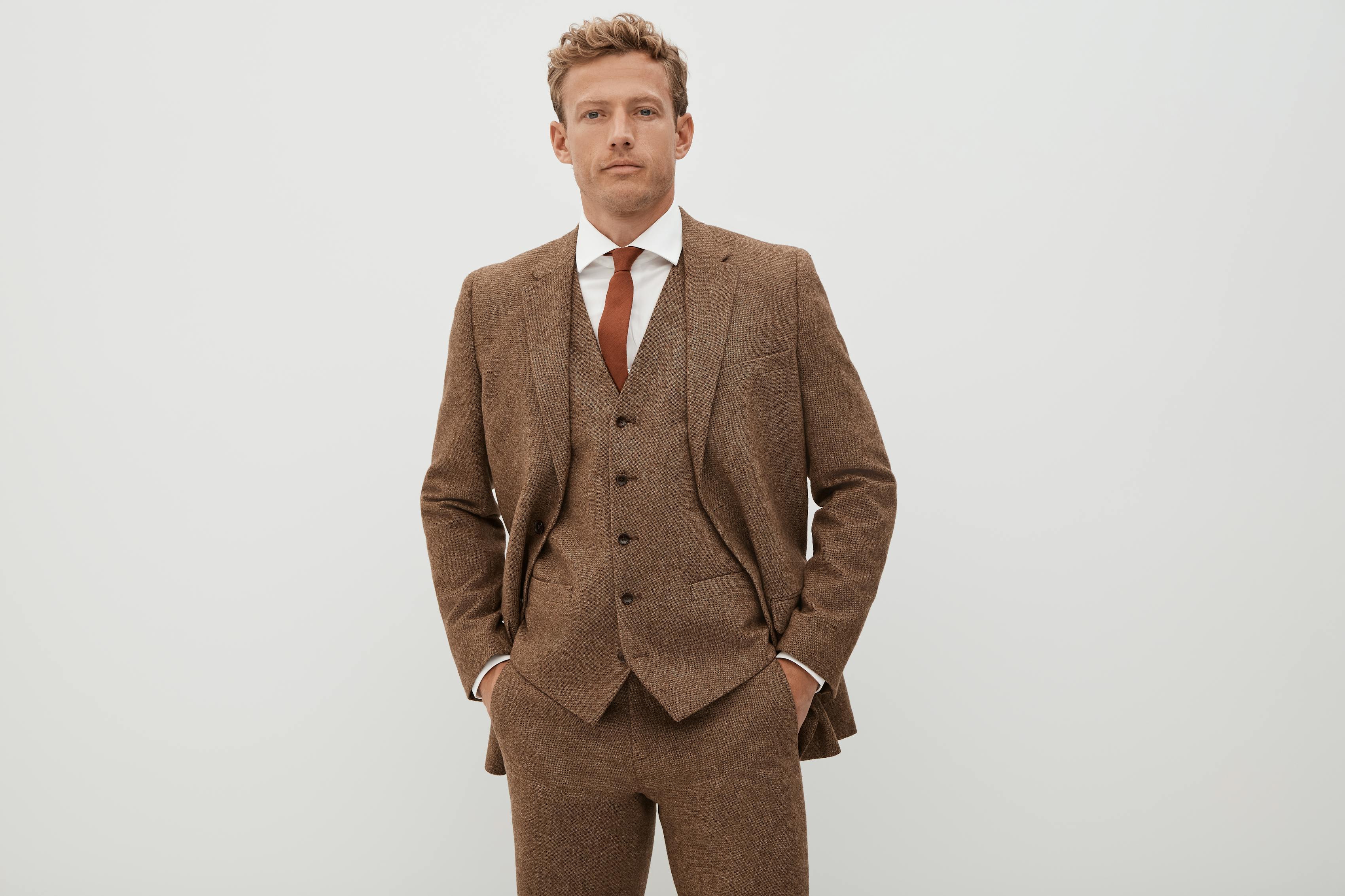 Men's three piece brown tweed suit styled with a rust color necktie