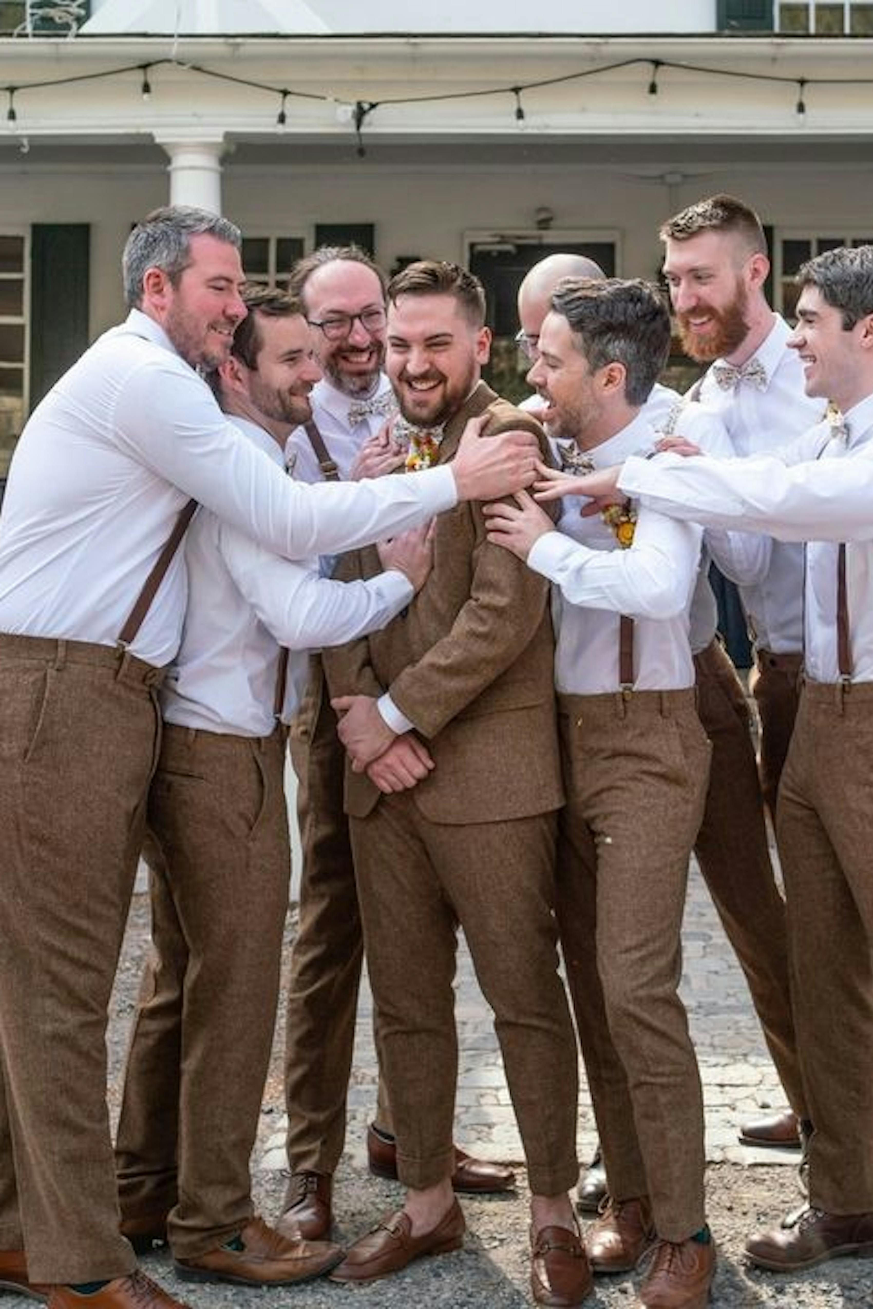 Groomsmen hugging photo wearing brown tweed wedding suits and suspenders