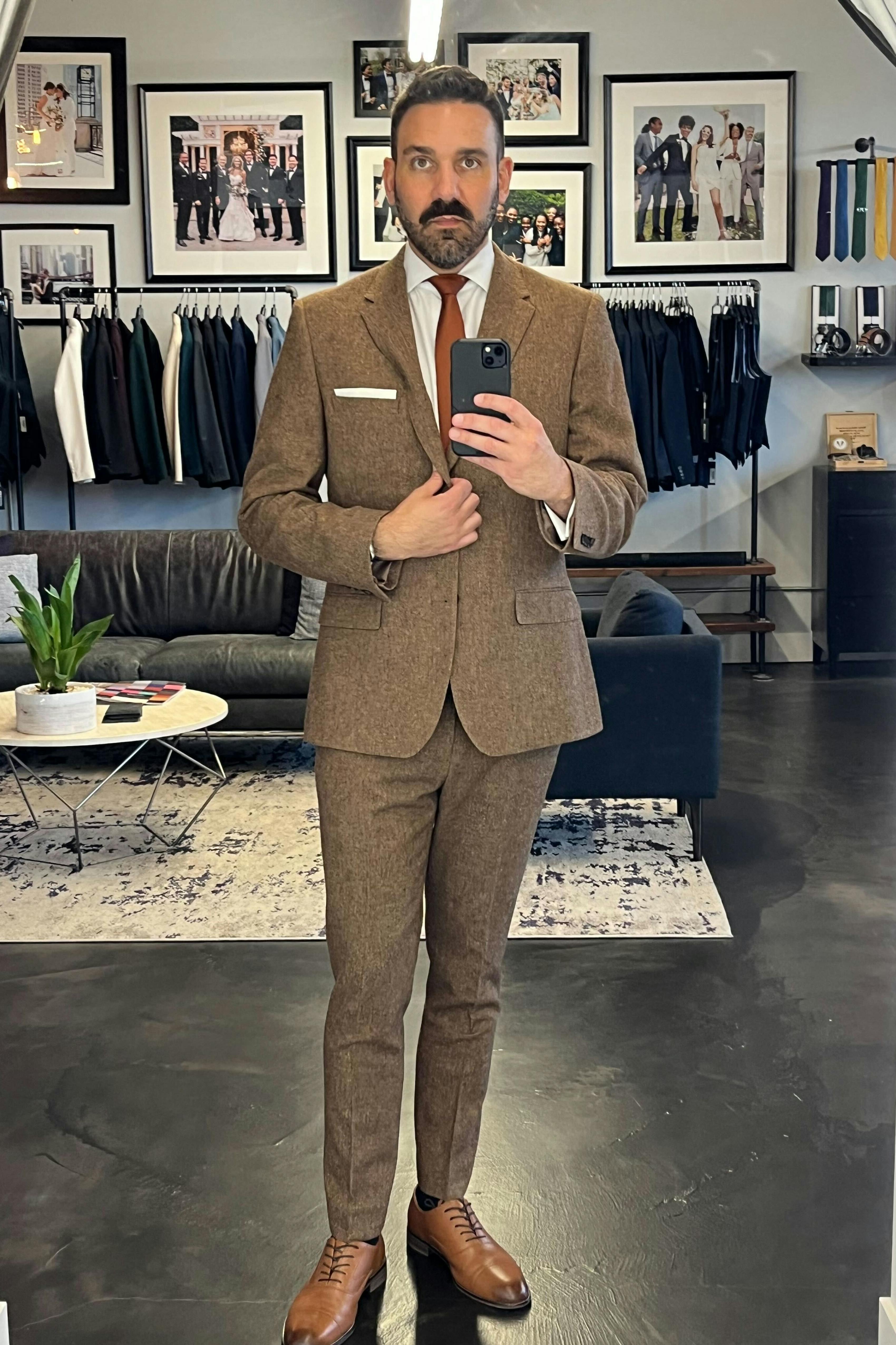 Man wearing a brown tweed single breasted suit jacket for men, taking a mirror selfie