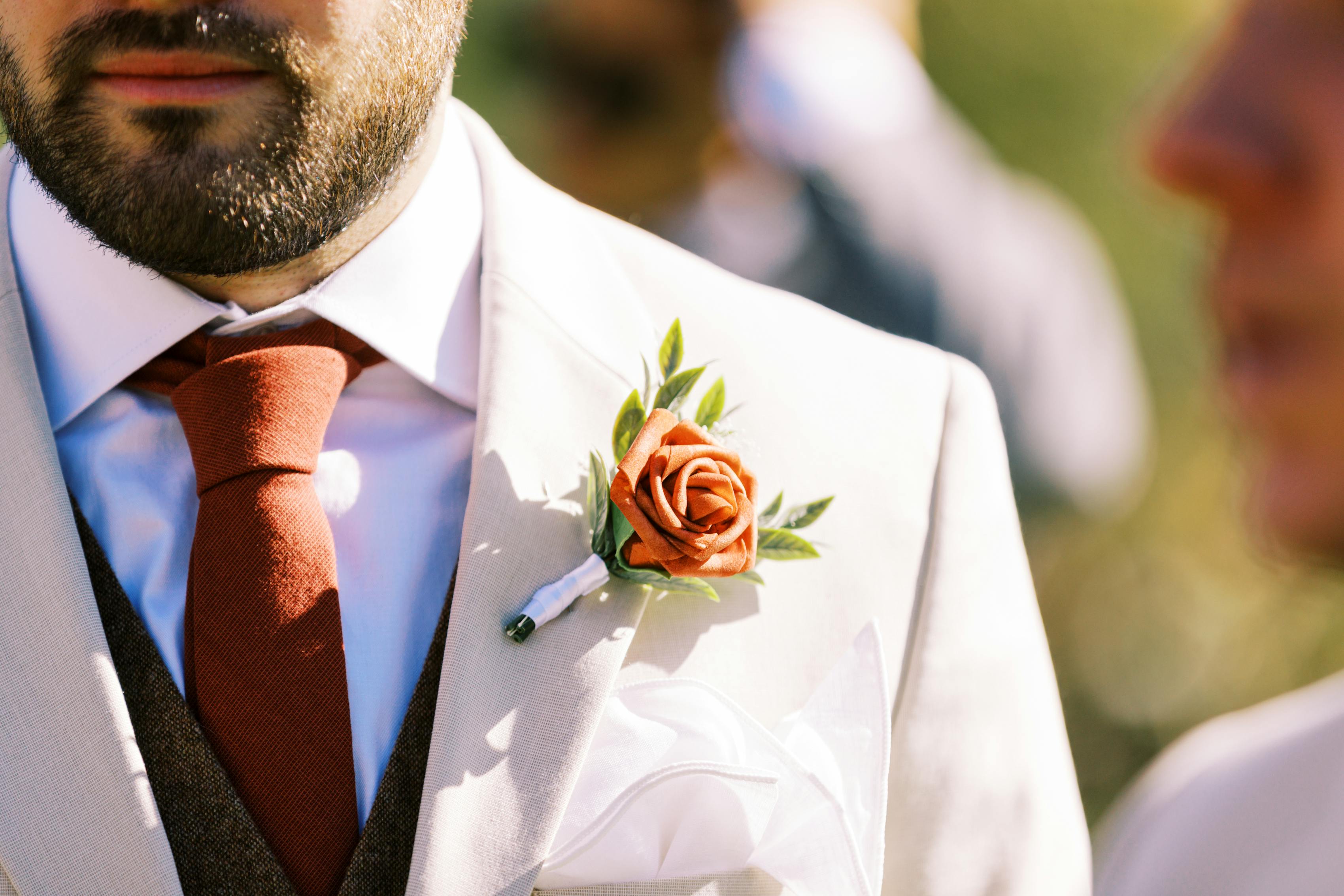 Groom in tan wedding suit and tweed vest for men with burnt orange accessories