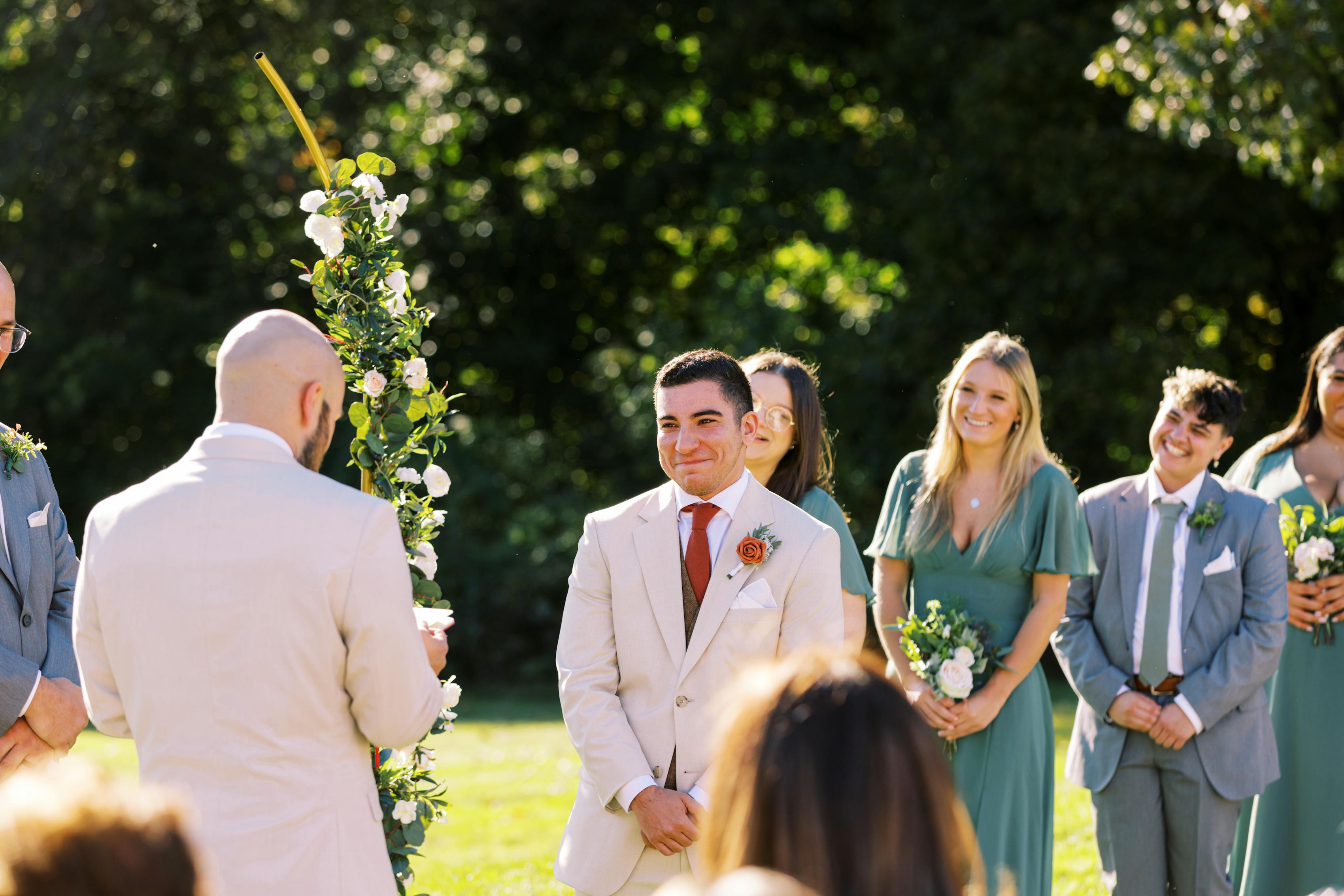 Grooms share heartfelt glance at the altar, wearing tan suits