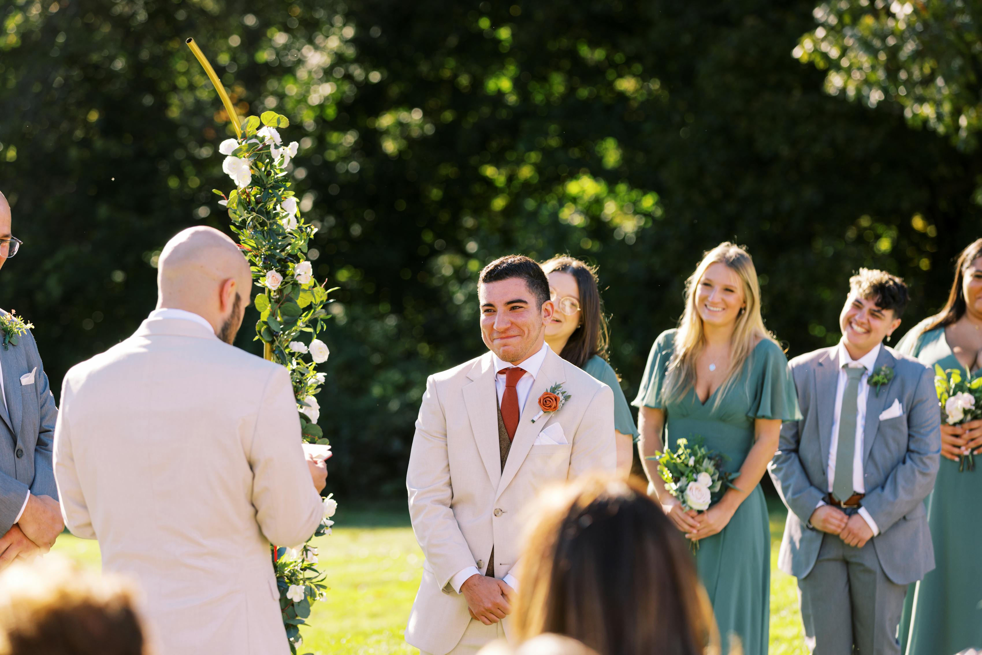 Grooms share heartfelt glance at the altar, wearing tan suits