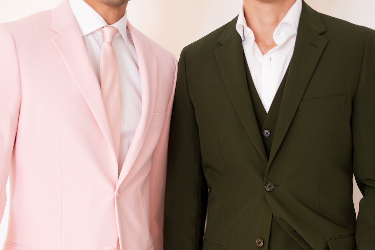 Trendy suits for men with a blush pink suit jacket and olive green men's suit in a classic cut.