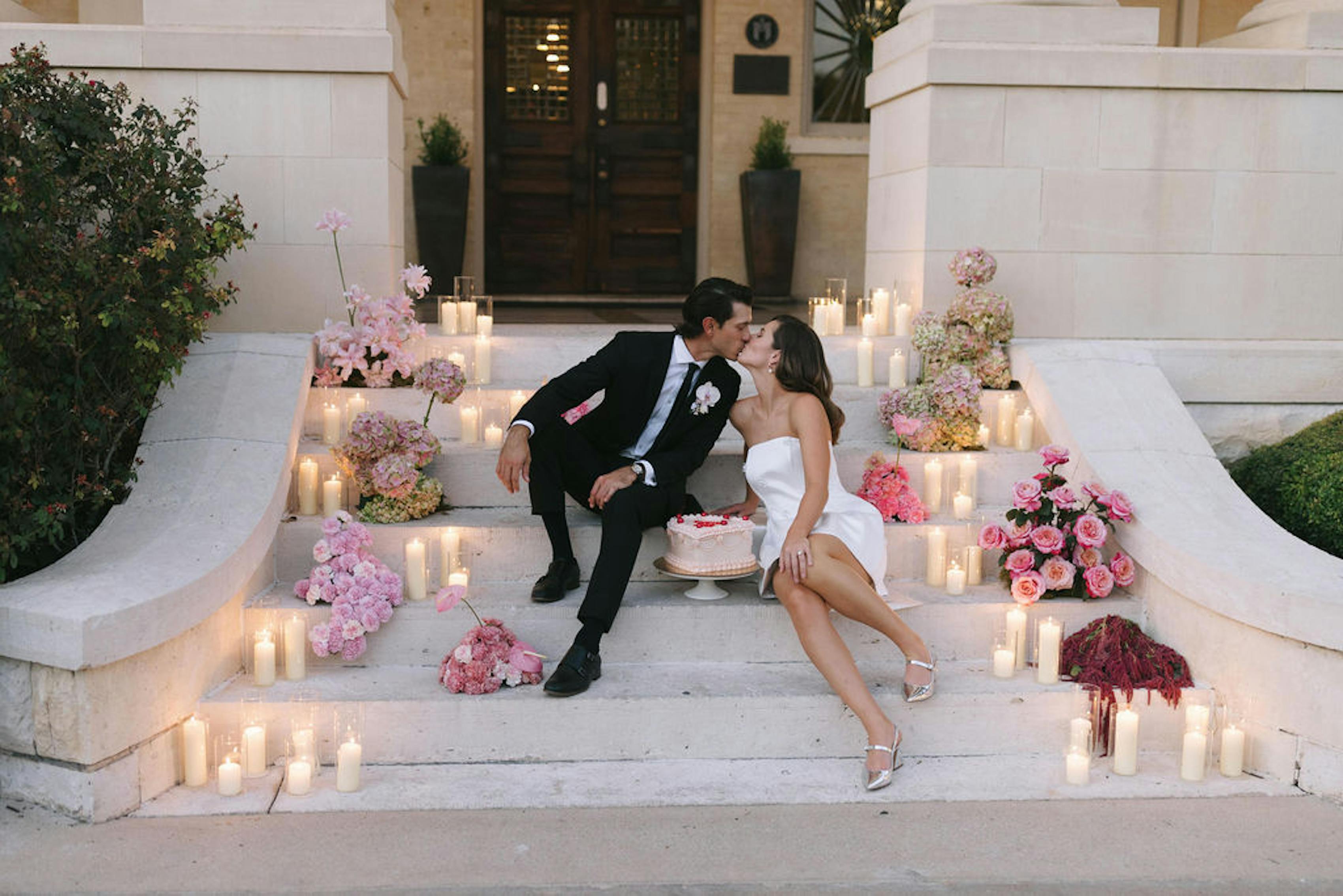Elegant wedding photo idea couple on steps lined with red and pink roses and white candles