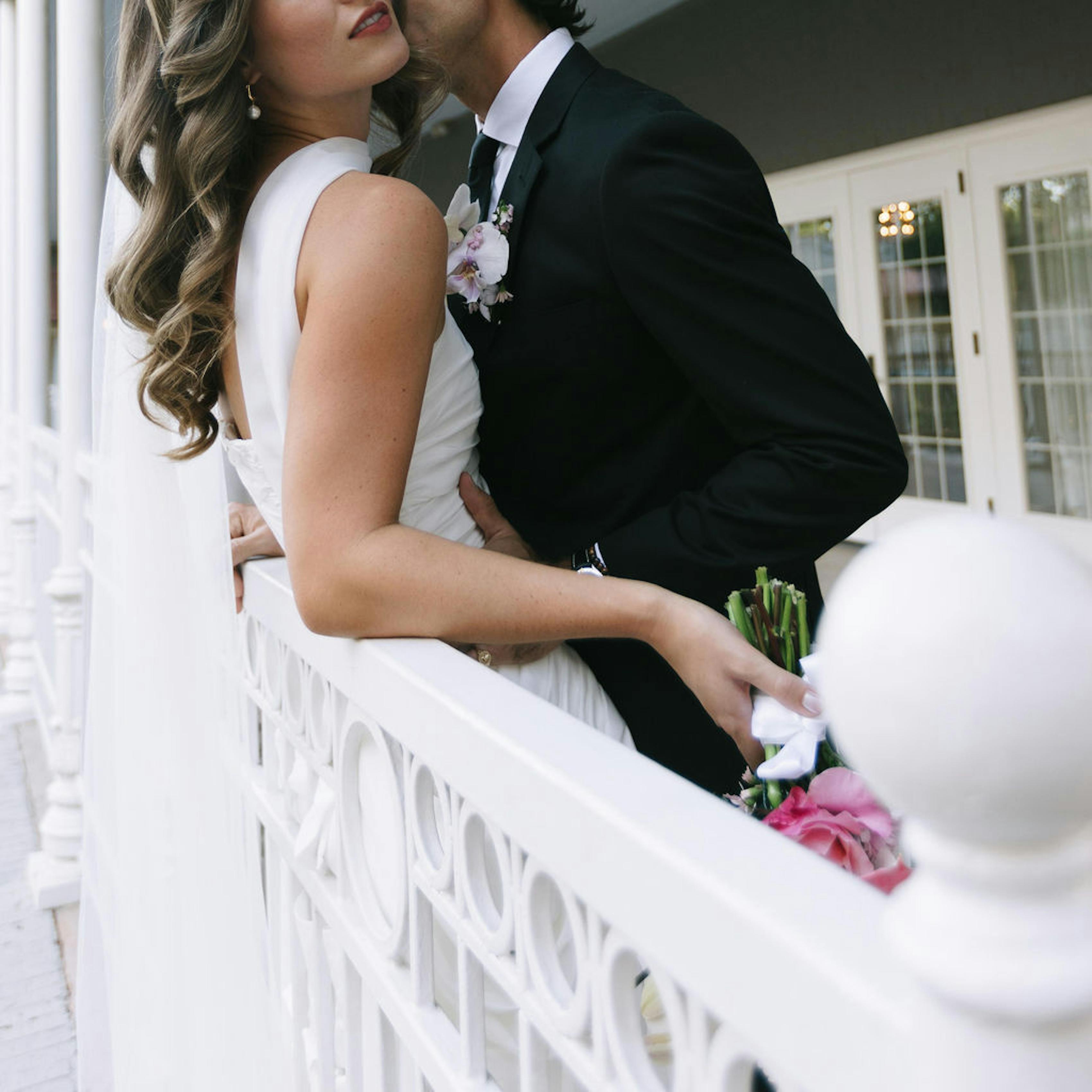 Intimate wedding attire with long bridal veil and black suit for the groom