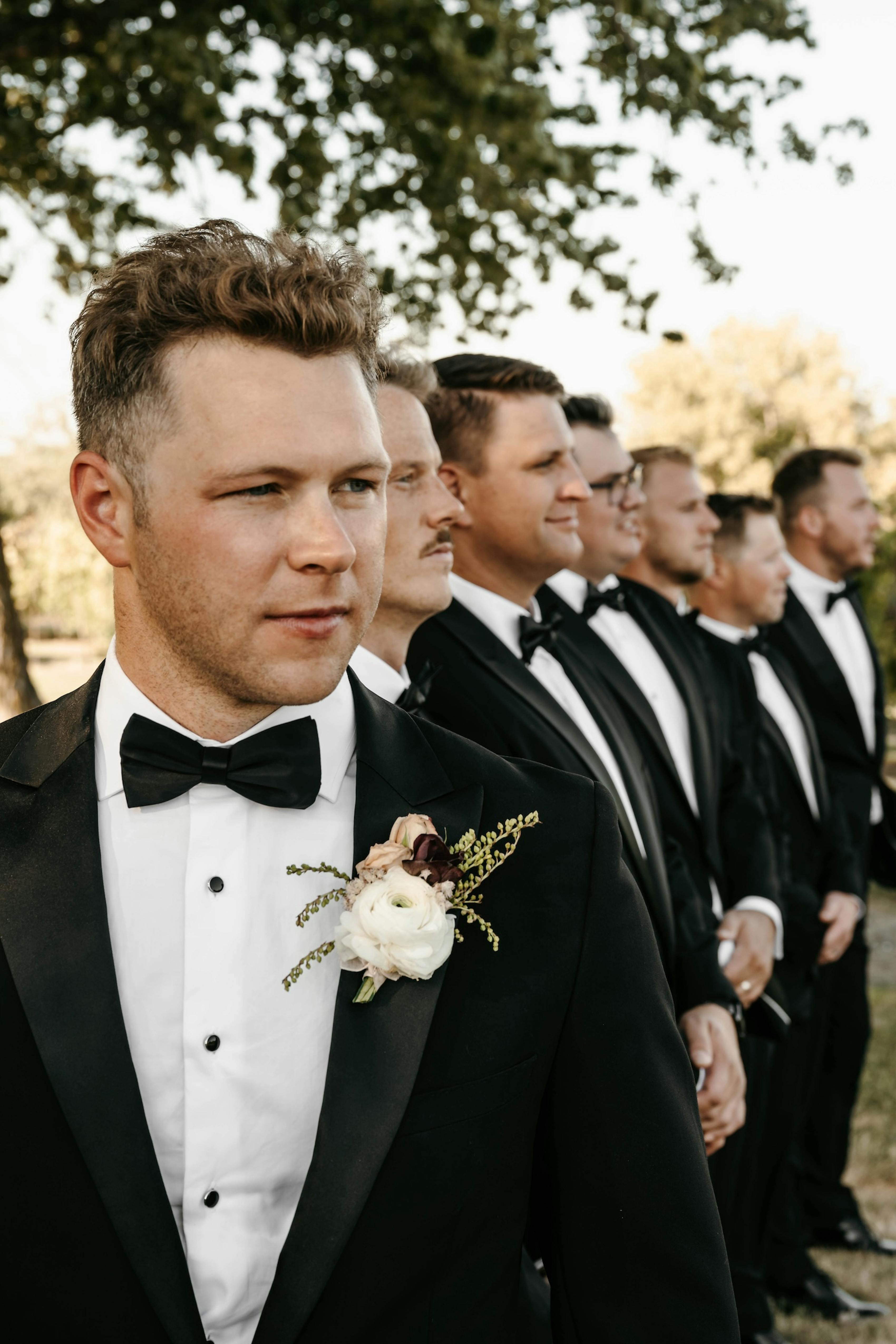group of groomsmen in peak lapel black tuxedos and black bow ties