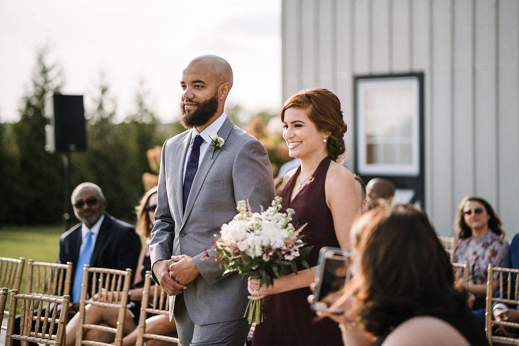 Grey groomsman suit with burgundy bridesmaid dress walking down the aisle