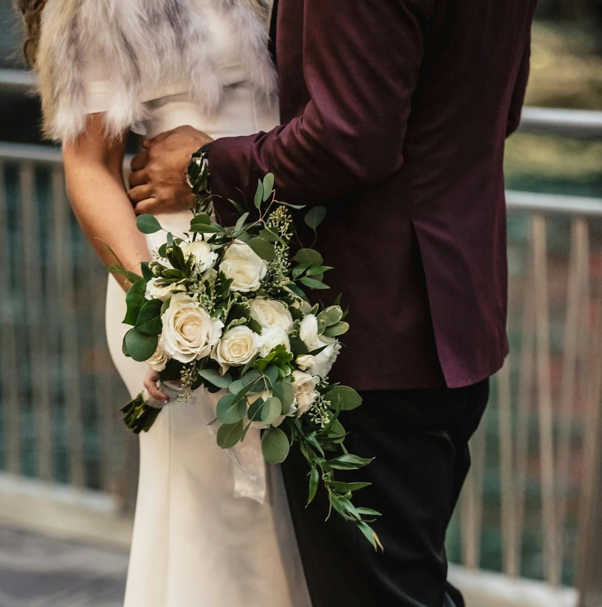 Winter wedding with sage green and burgundy color palette in maroon tuxedo and eucalyptus bouquet