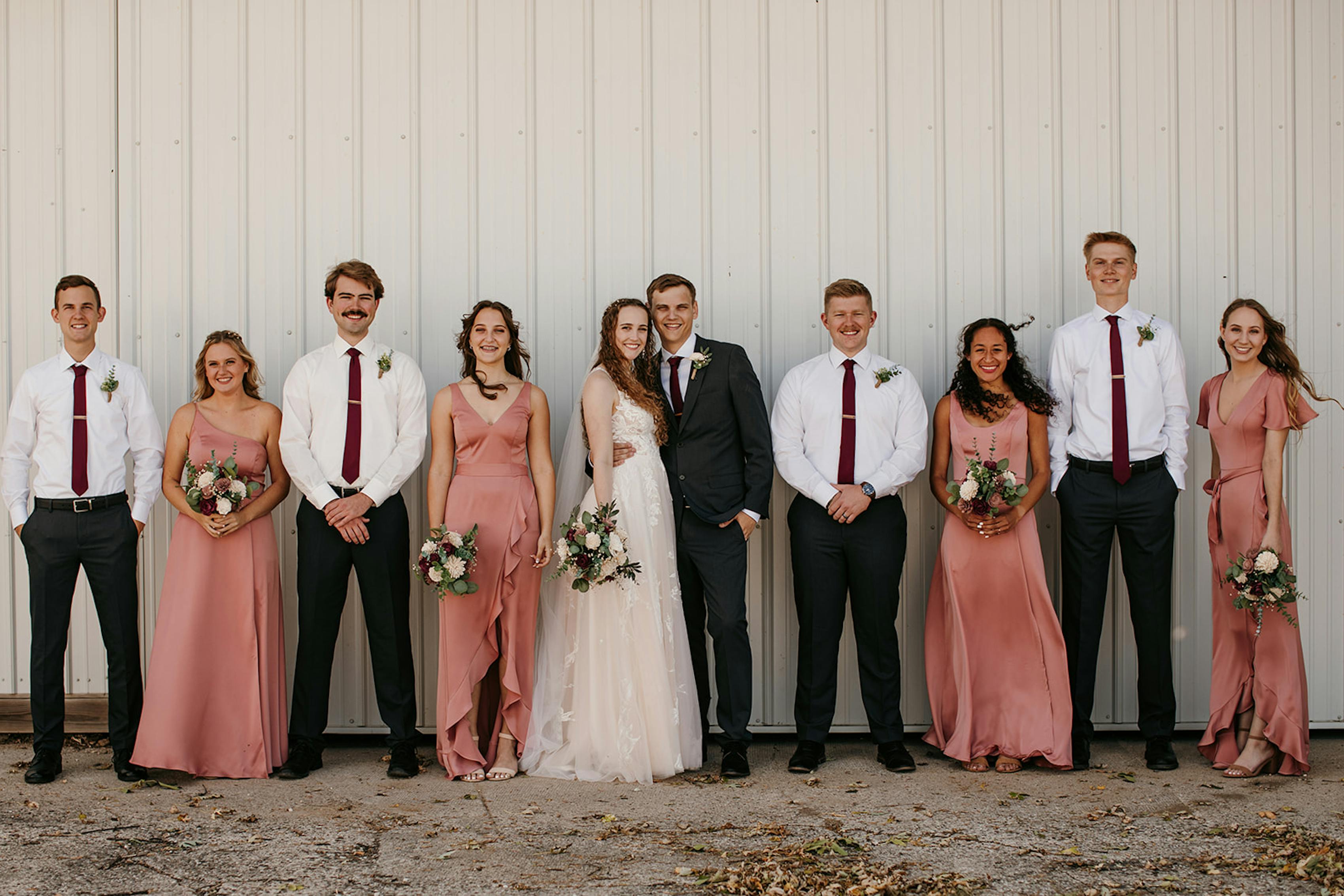 Charcoal grey groomsman suits with dusty rose bridesmaid dresses and maroon ties