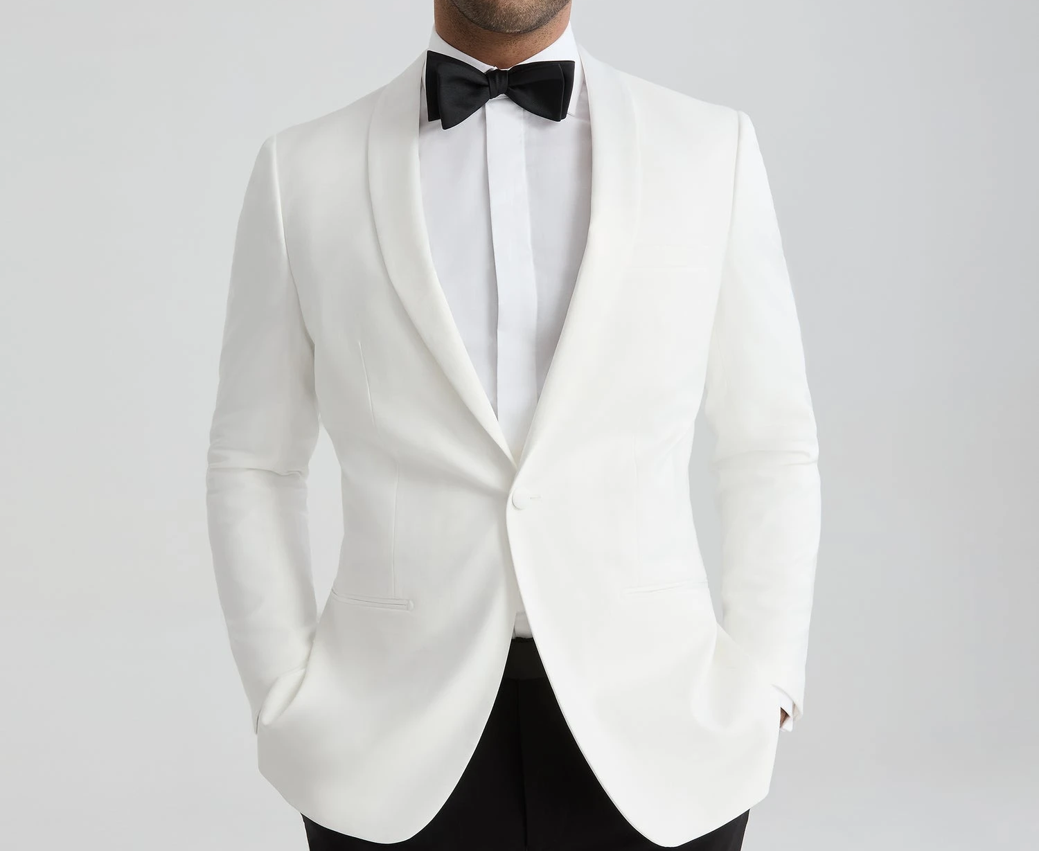 White dinner jacket with black bow tie and formal black trousers for a wedding or black tie event.