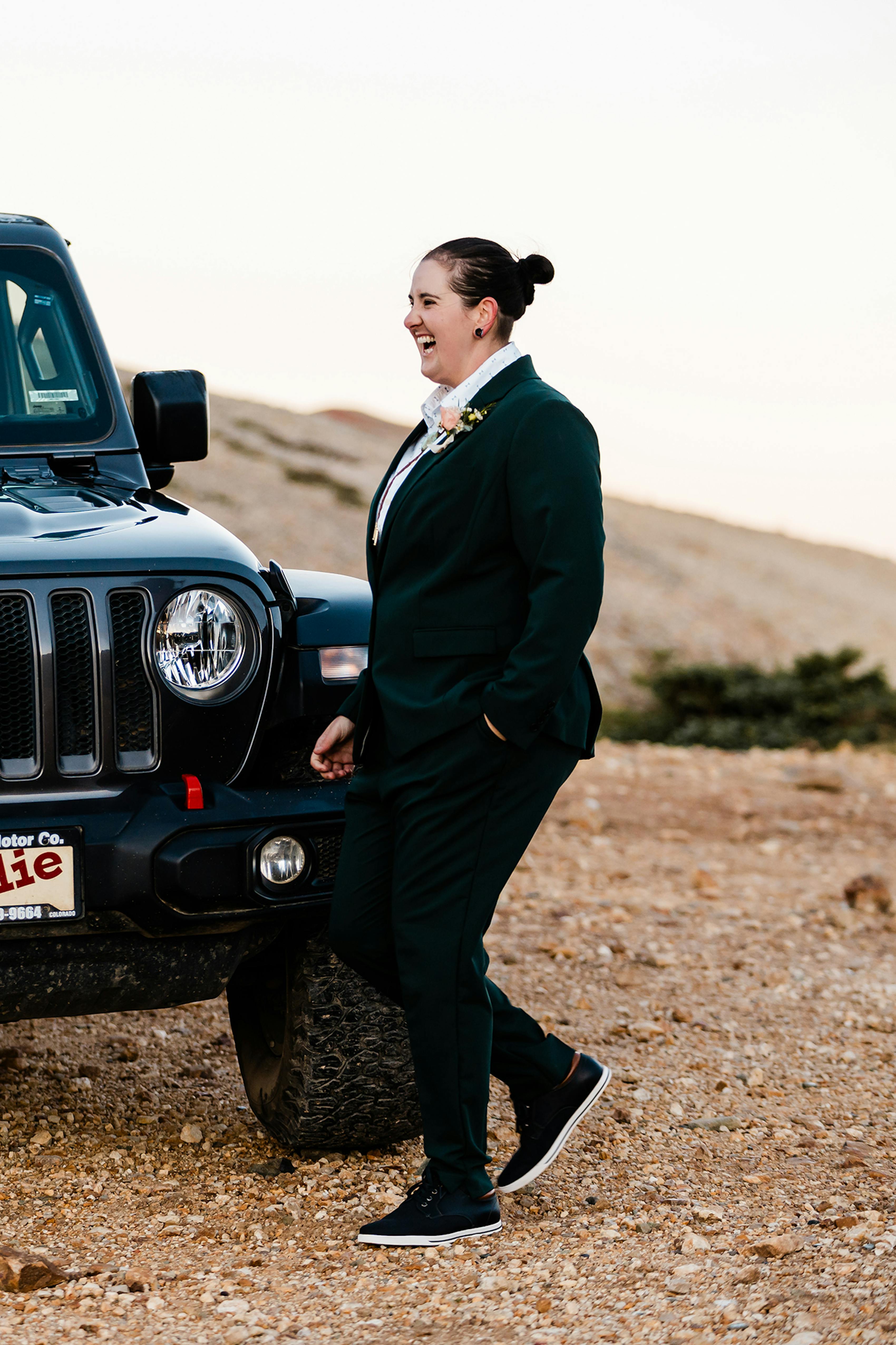 Laughing wearing a masculine bridal suit in dark green.