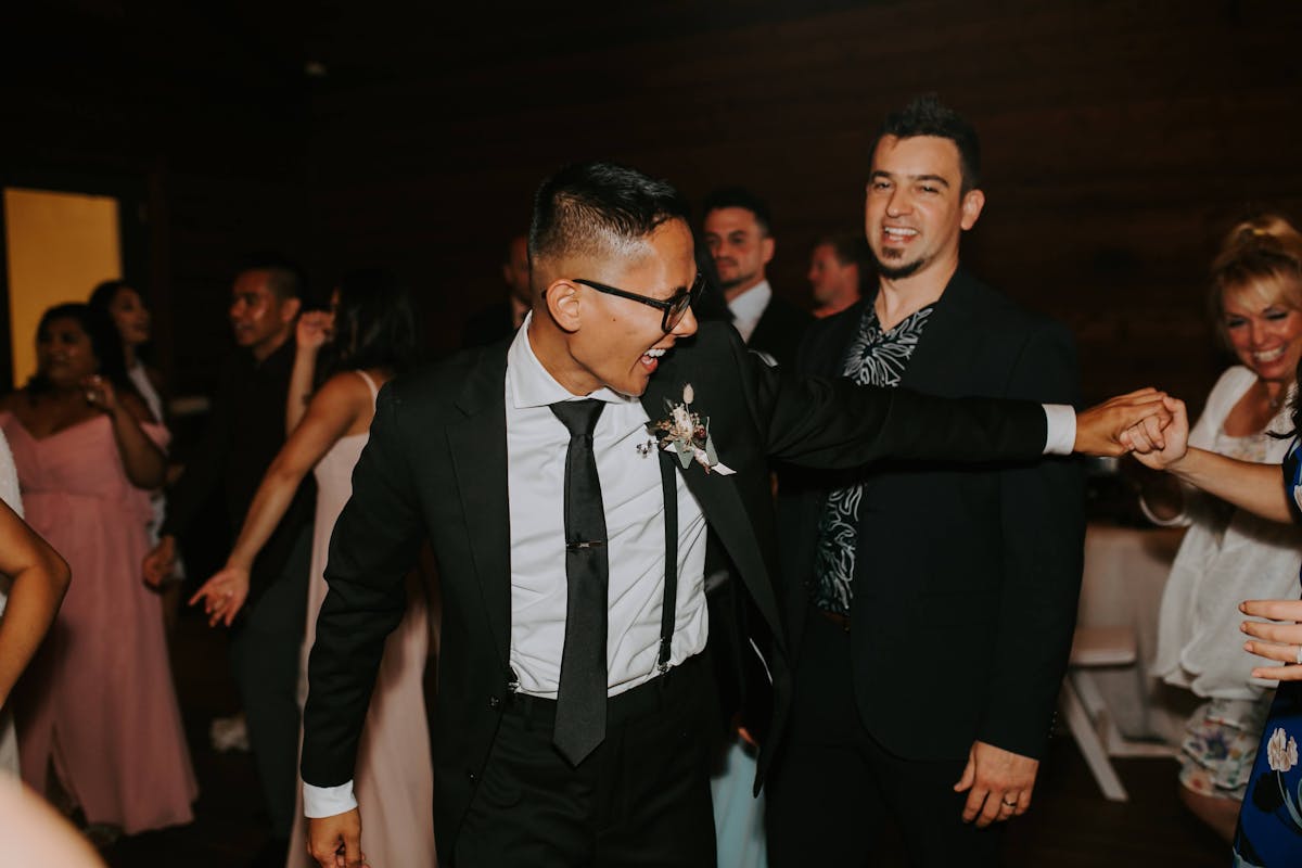 Rowdy wedding dance floor groomsman black suit and suspenders at wedding reception.