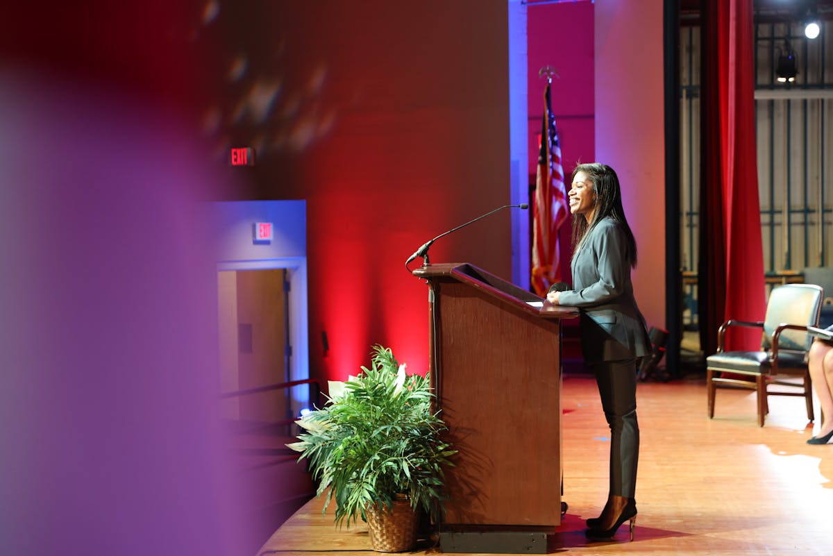 Woman dressed professionally in a dark grey blazer presenting at a podium for law school ceremony.