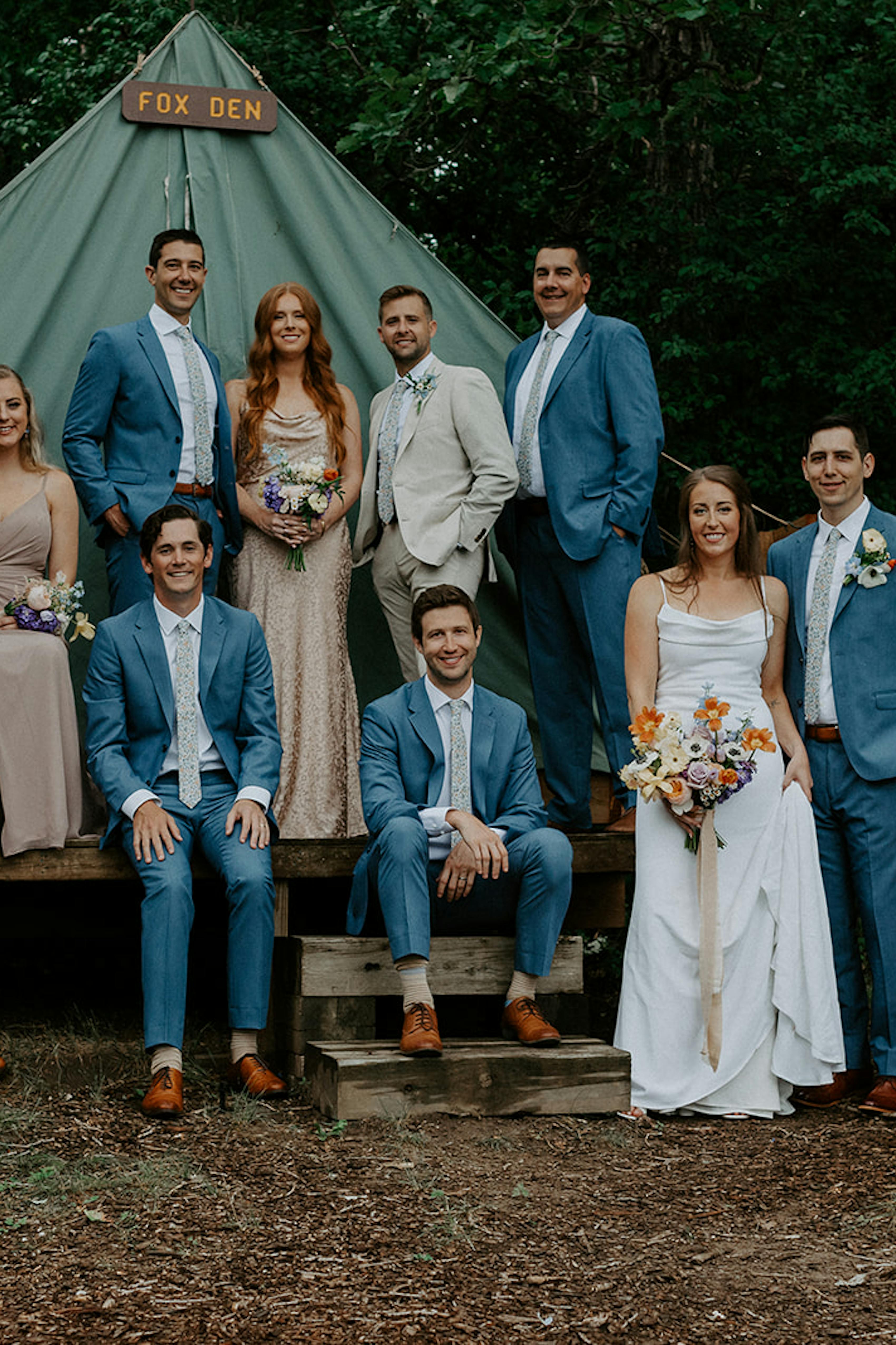 Summer camp themed wedding with groomsmen and bridesmaid posing with tent