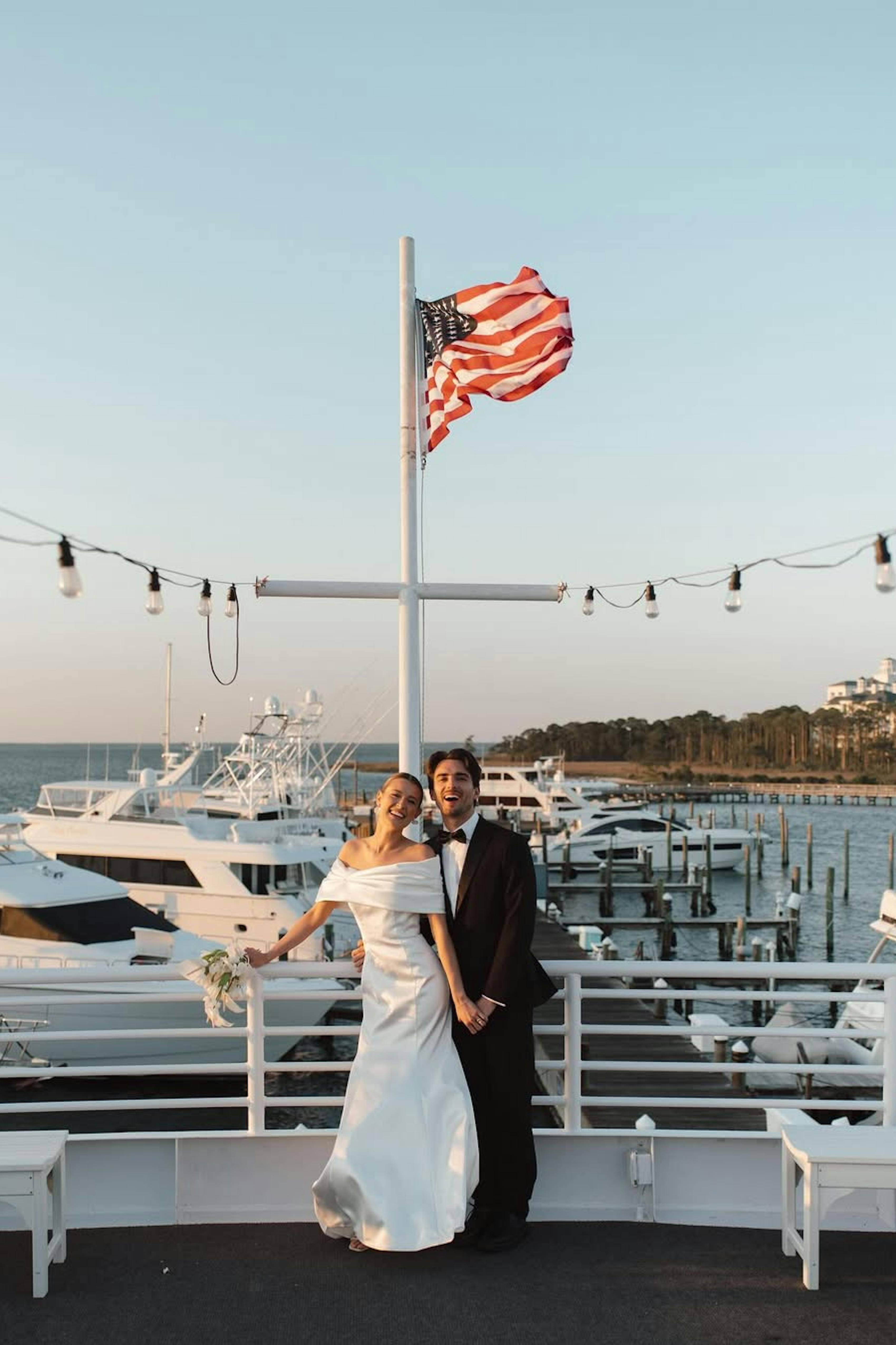 Nautical wedding on a yacht wearing simple bridal gown and groom's black tuxedo