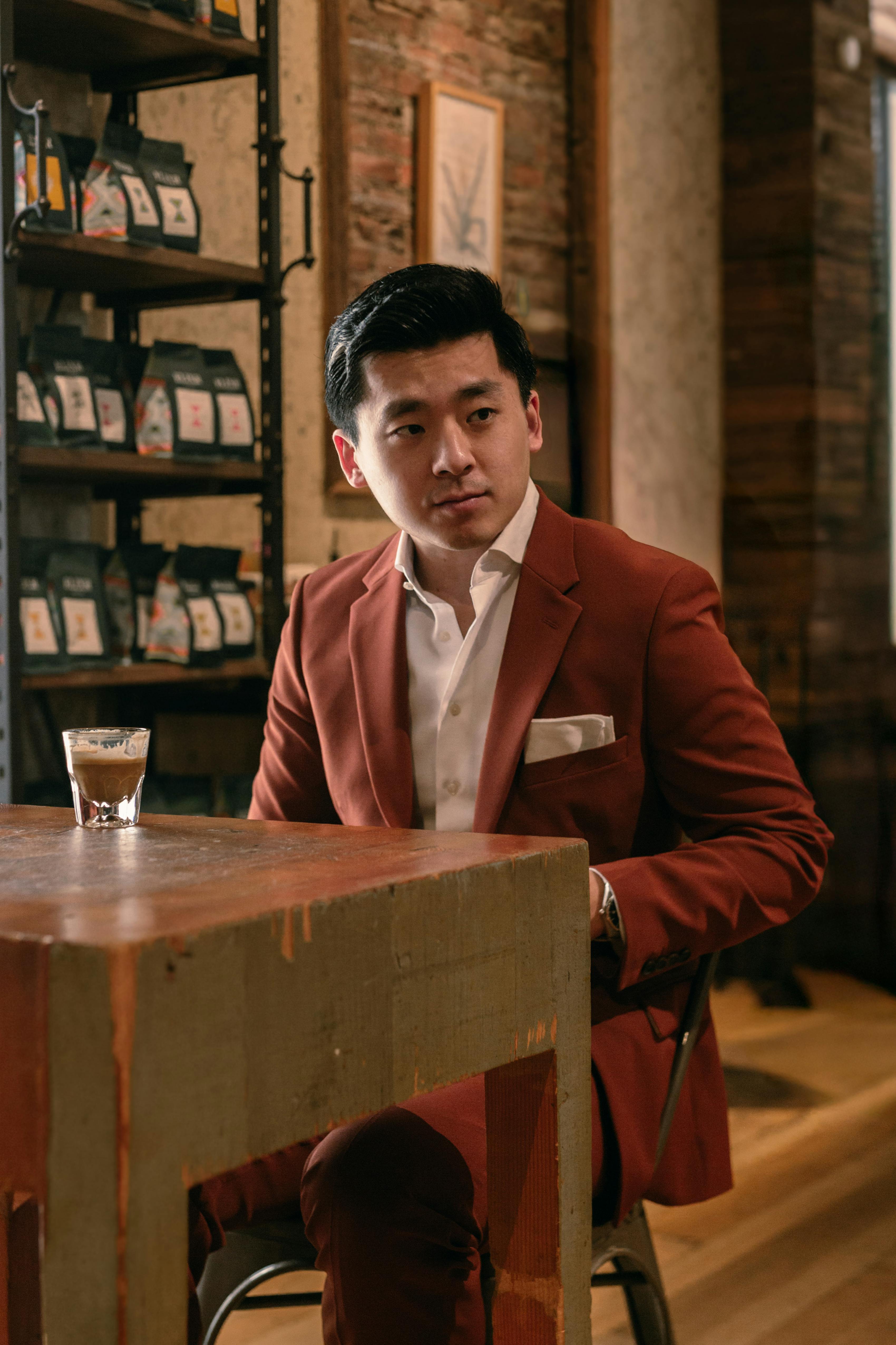Casual menswear style in bold orange clay suit without tie at coffee shop