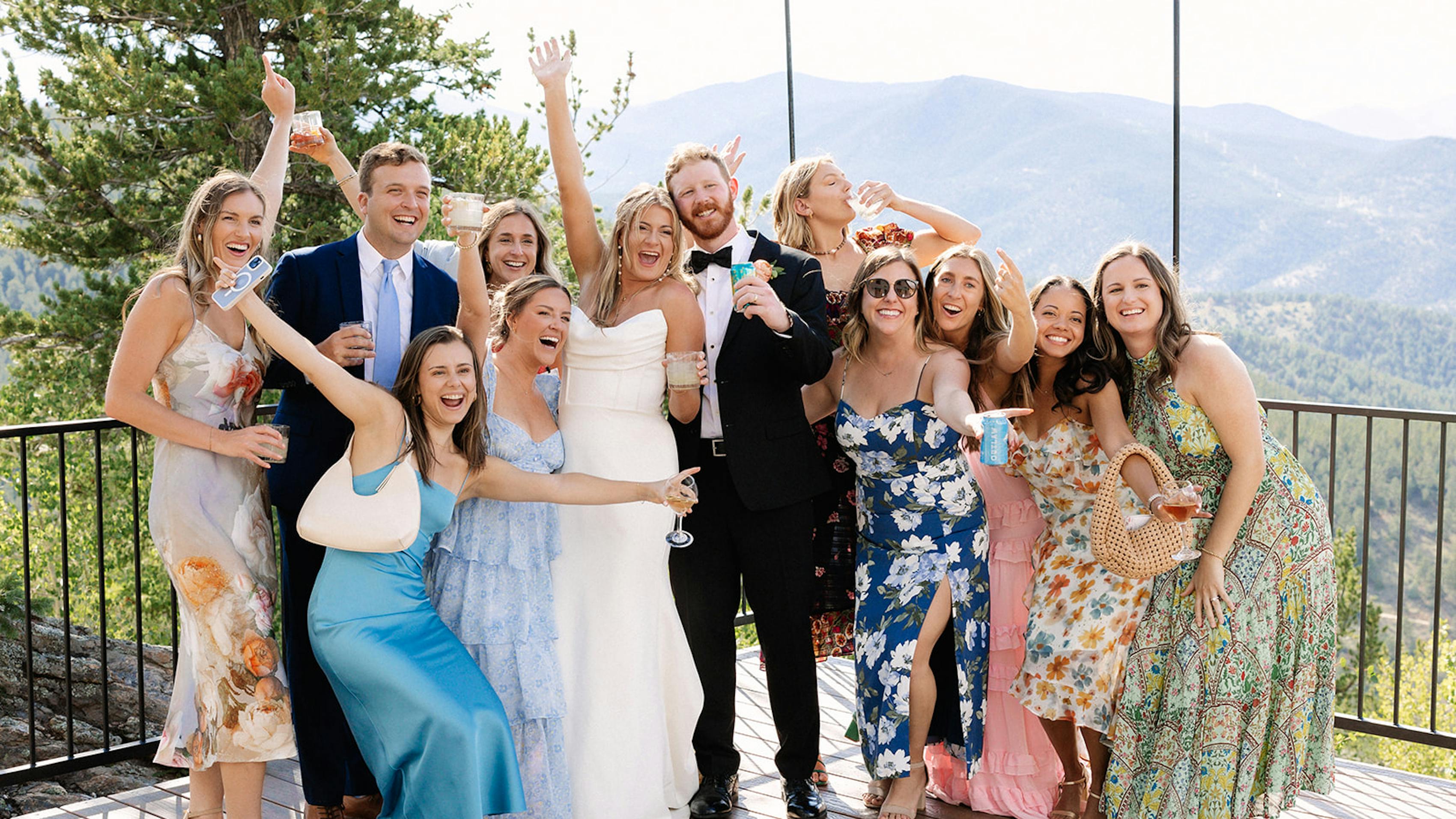 Partying guests in pastel and floral dress code for outdoor mountain wedding