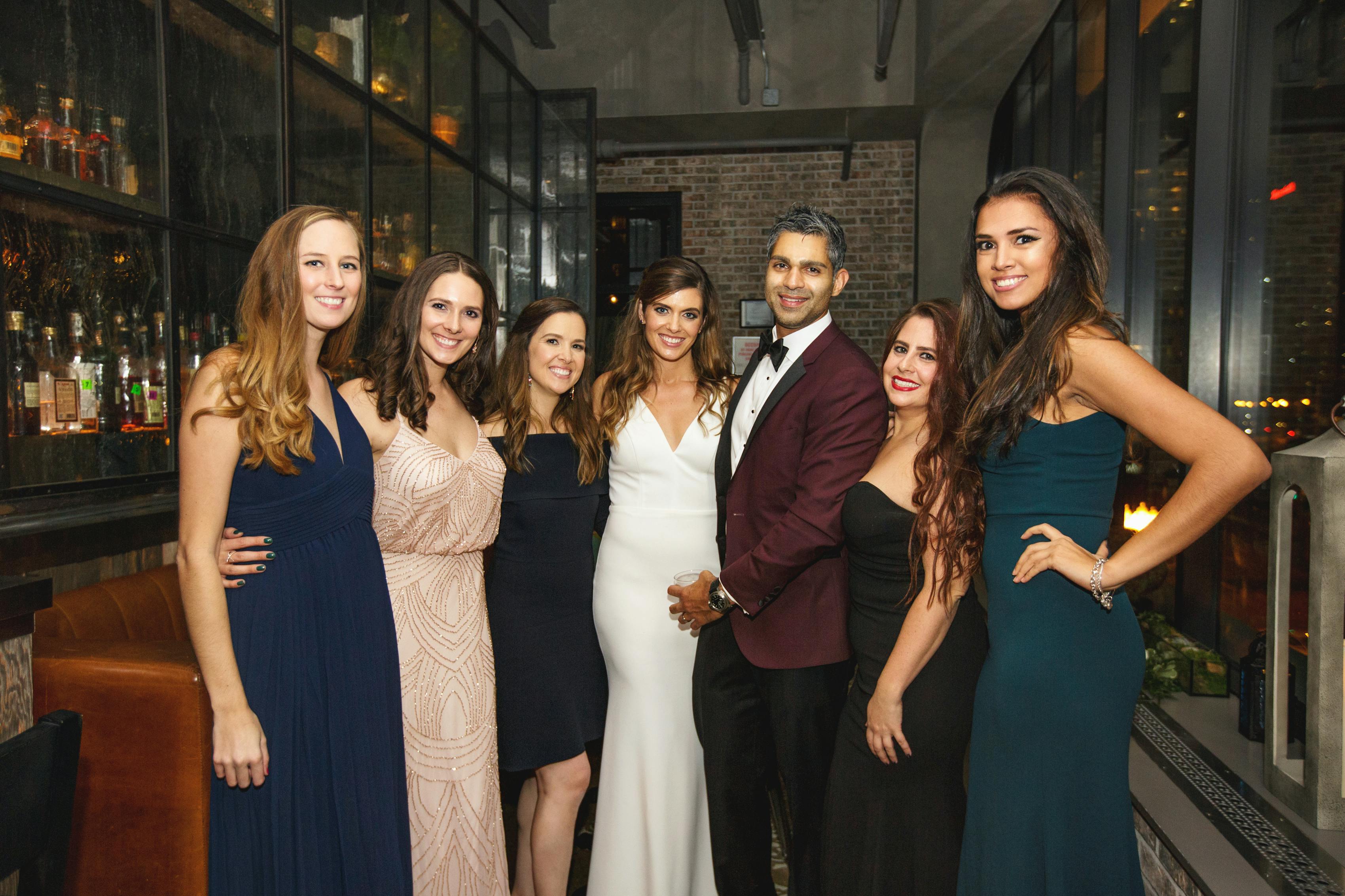 Bride, groom, and wedding guests in jewel tone wedding color palette attire and burgundy tuxedo