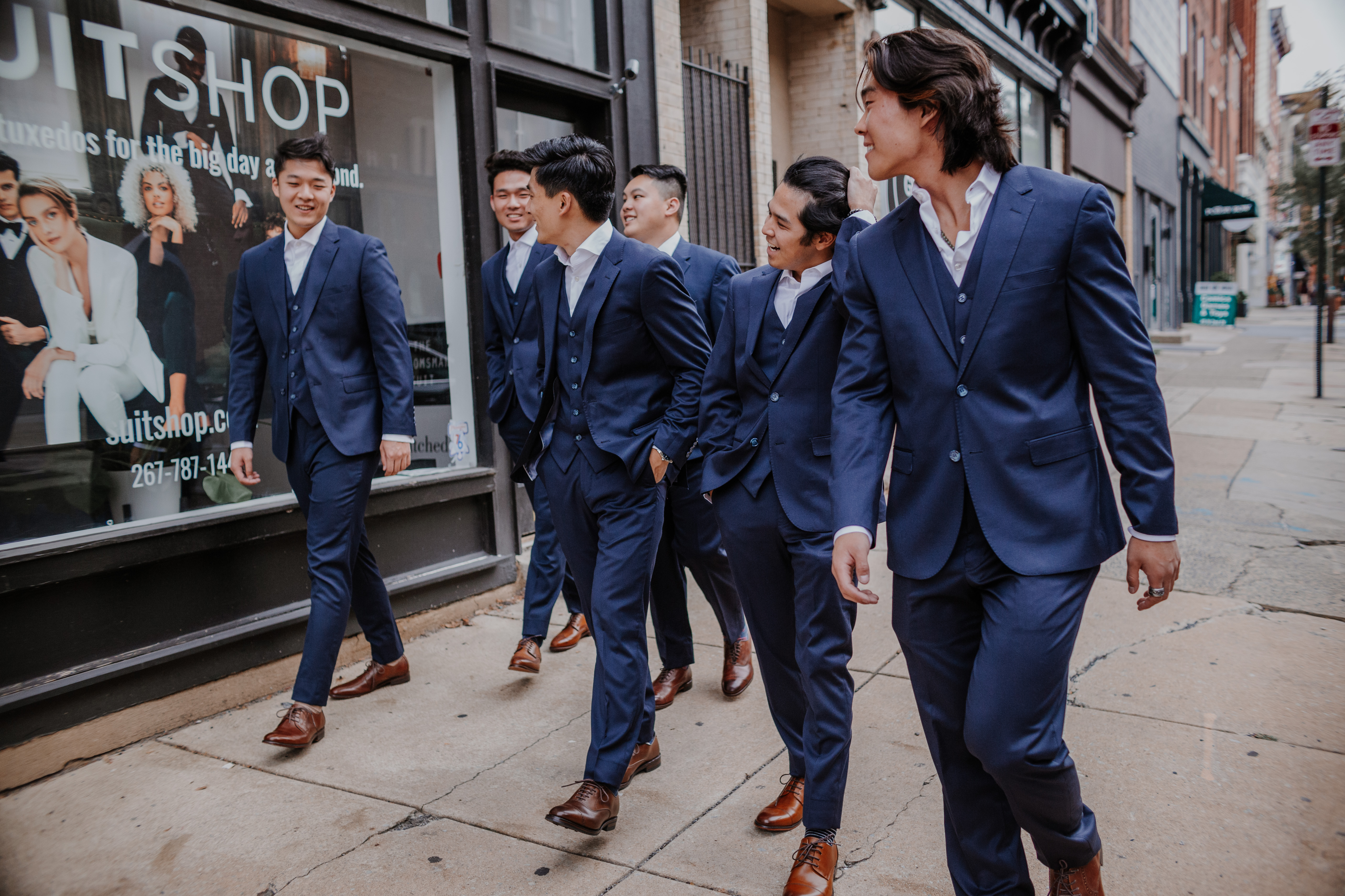 Fashionable groomsmen in navy blue suits and dark brown dress shoes walking down street