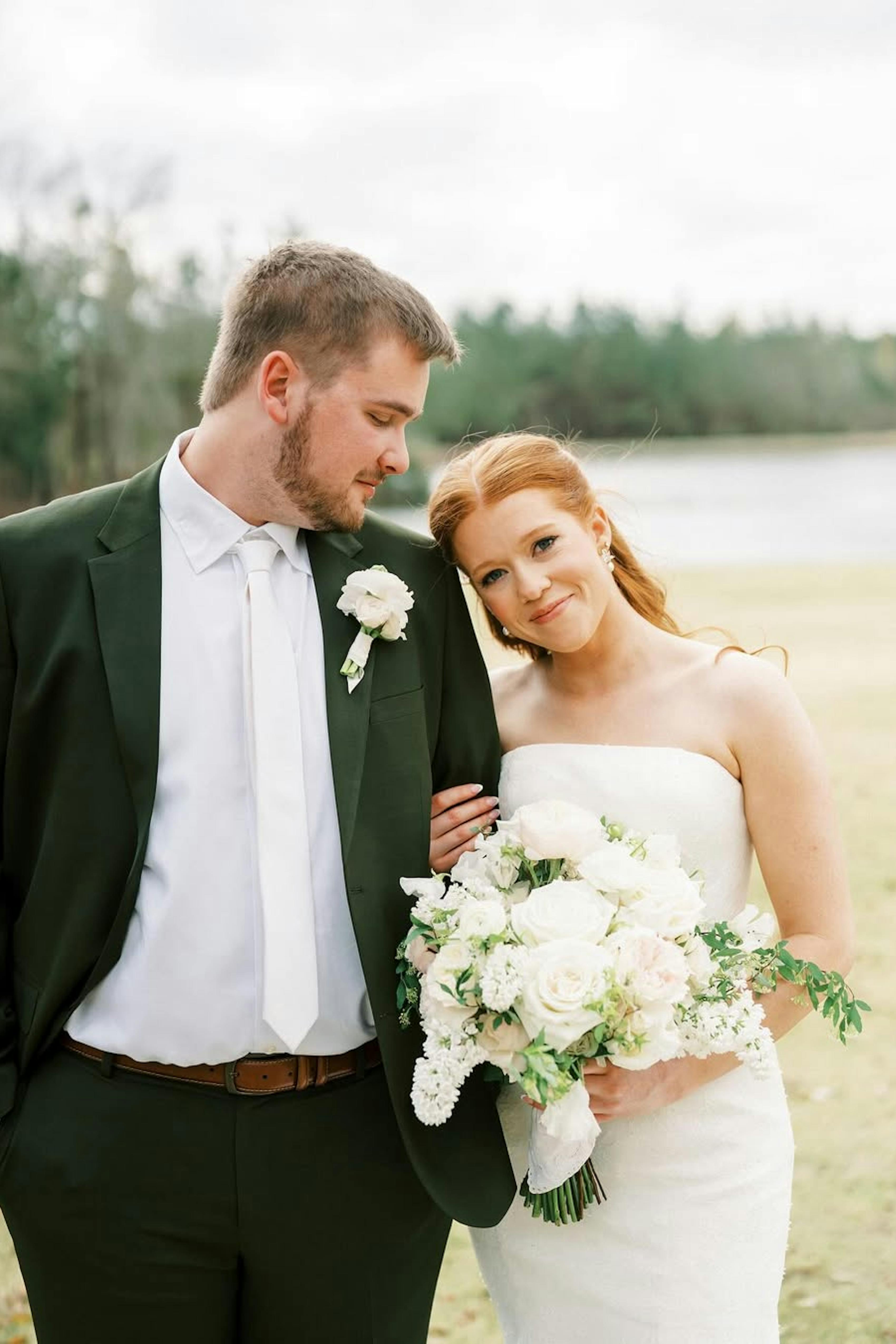 Groom wearing olive green suit and bride in strapless gown for outdoor wedding