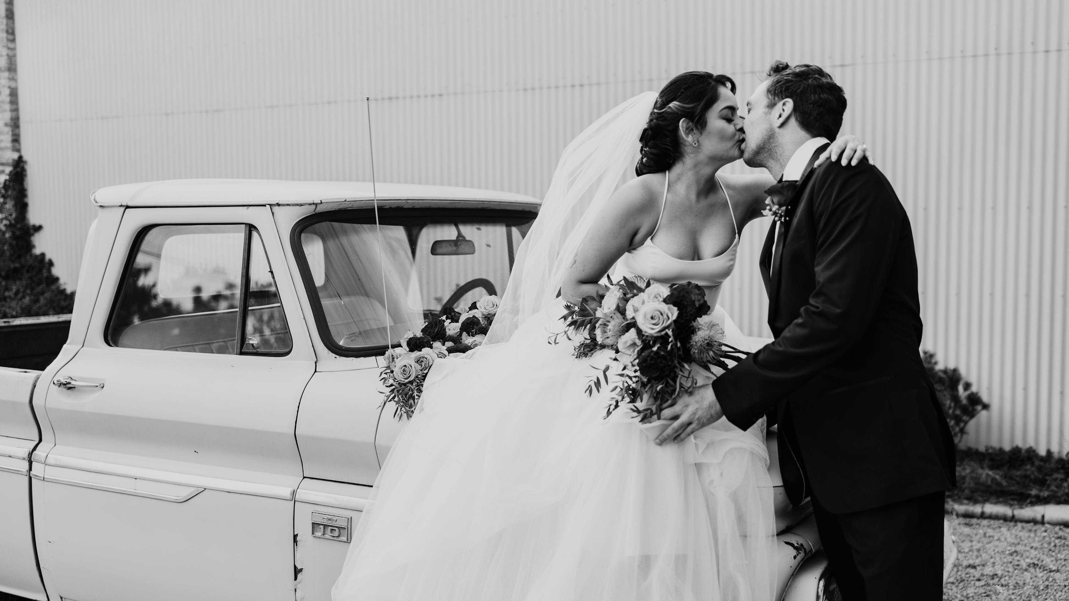 Vintage wedding theme with bride and groom posing with an old pickup truck