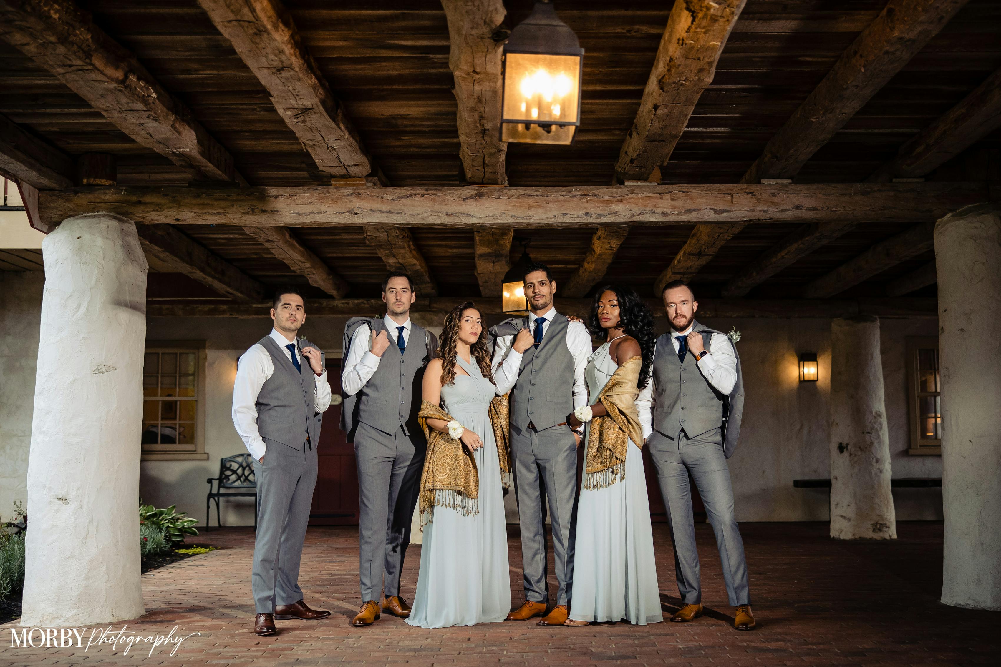 Vintage themed wedding party attire with light groomsmen grey suits and blue bridesmaid dresses