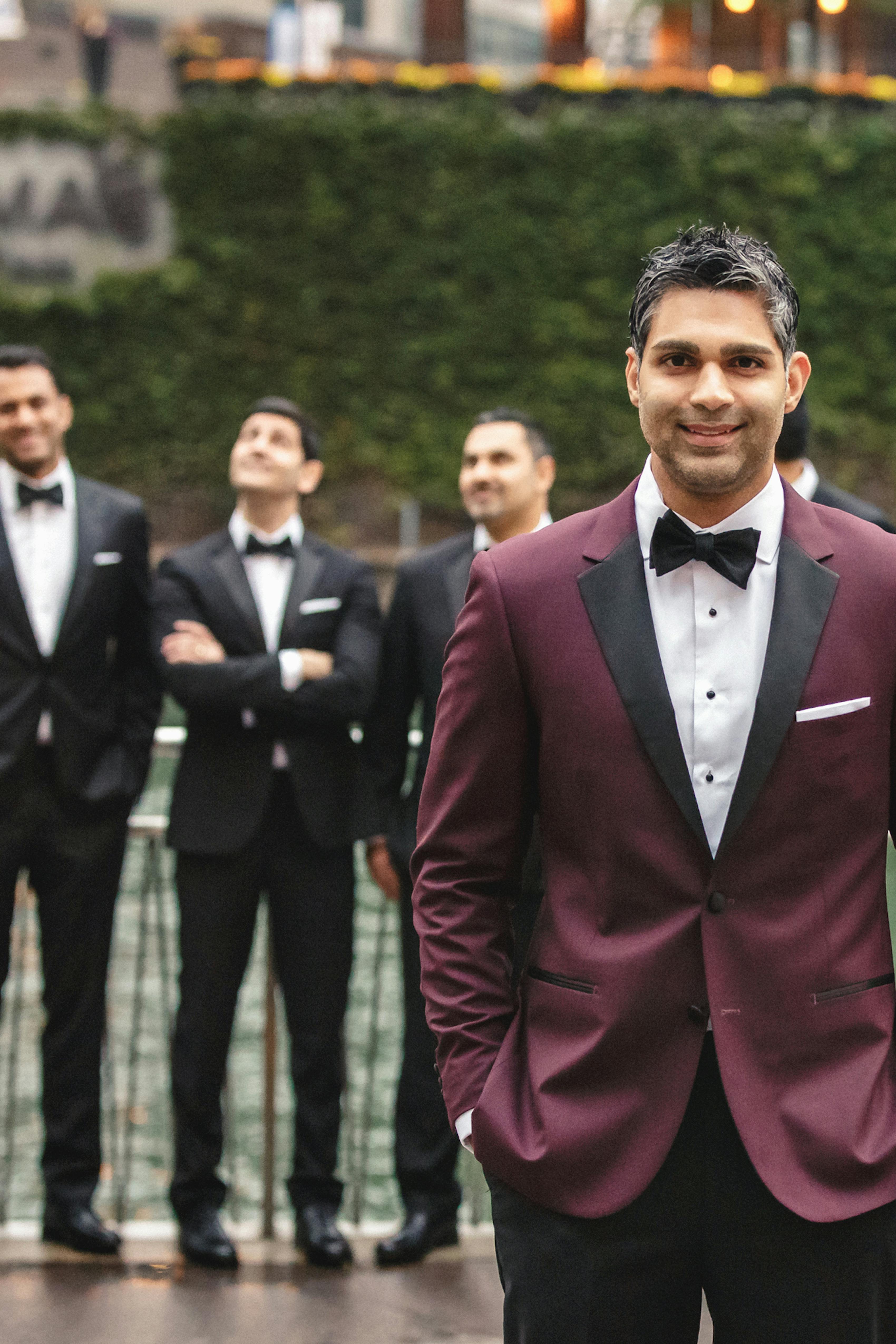 Burgundy groom tuxedo with black groomsmen tuxedos