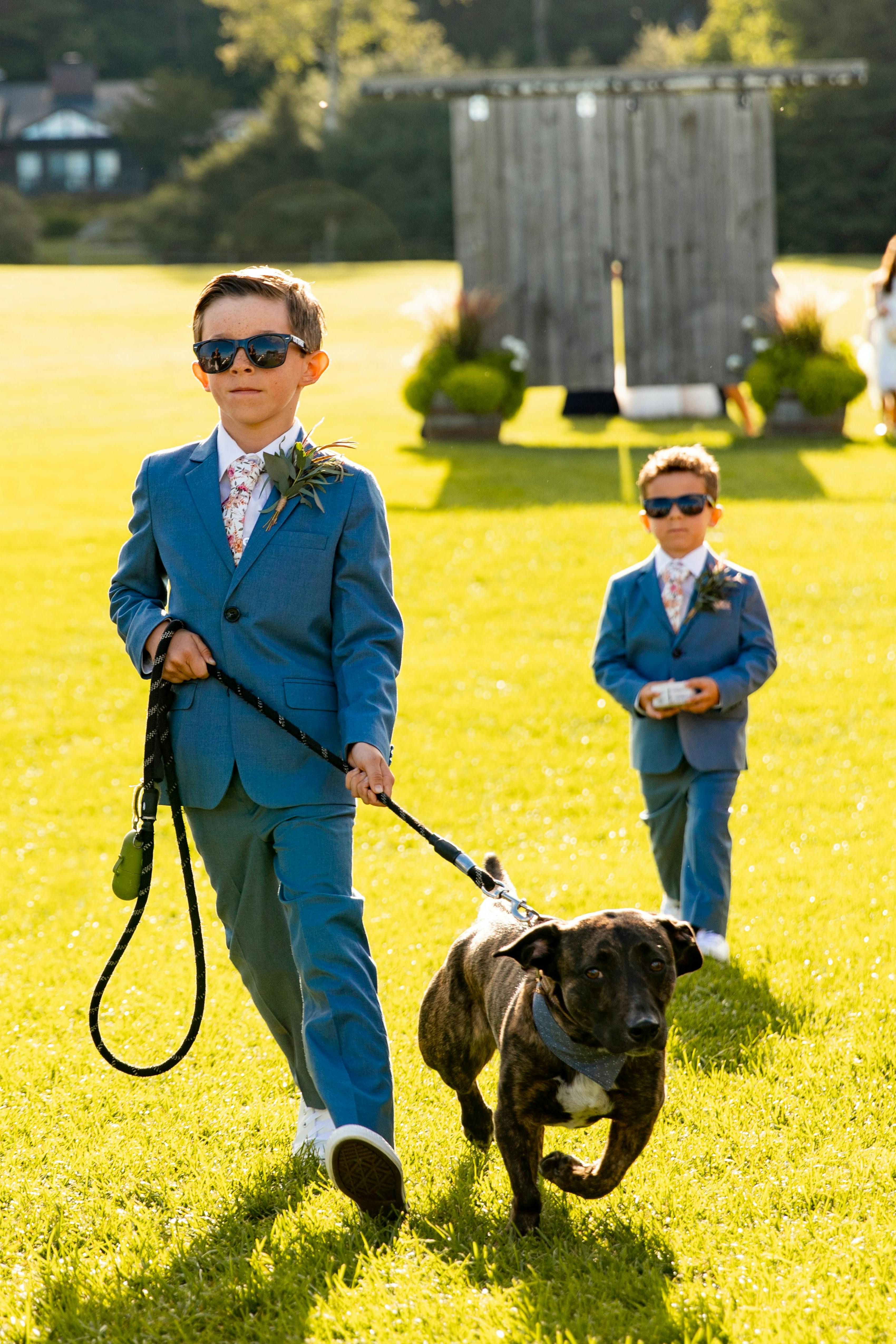 Ring bearers wearing matching light blue kid suits walking down the aisle
