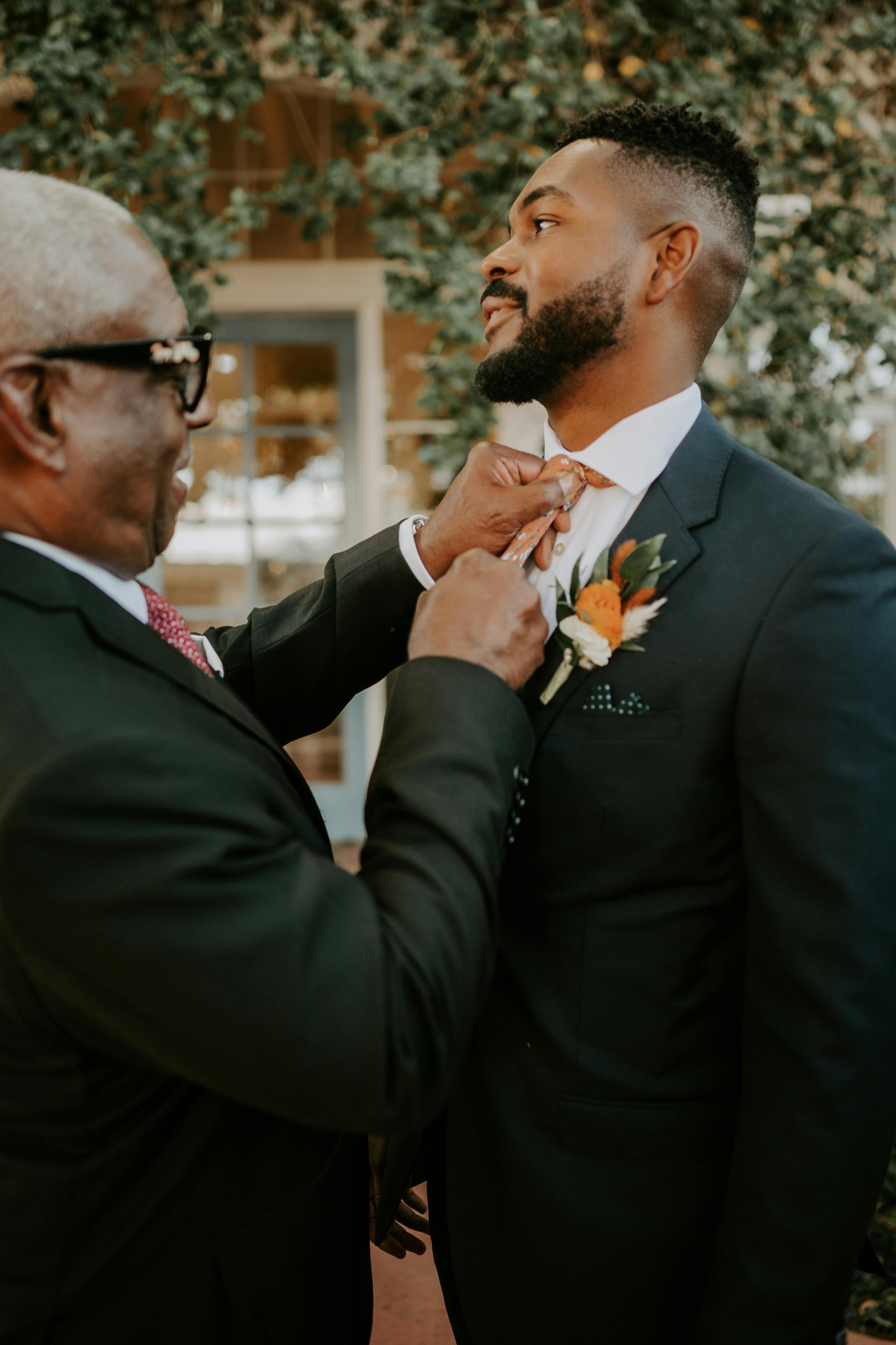 Groom and father getting ready in coordinating wedding suits with different accessories
