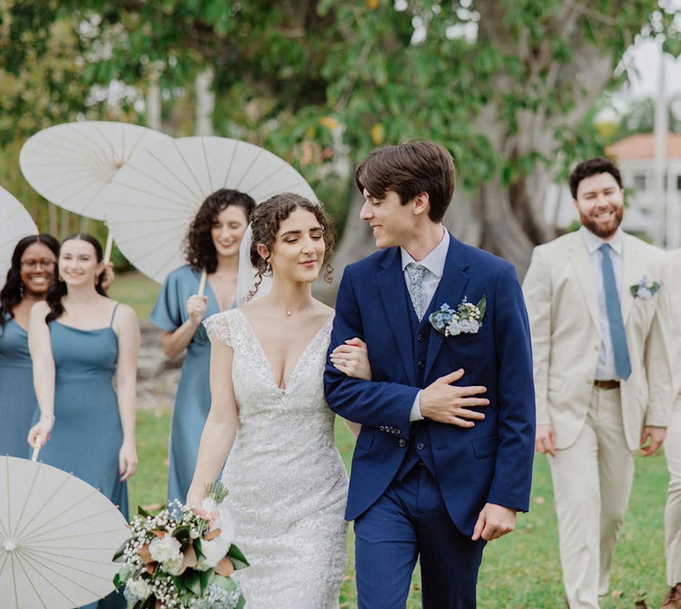 Wedding couple march in front of groomsmen in ivory white and bridesmaids in light blue.