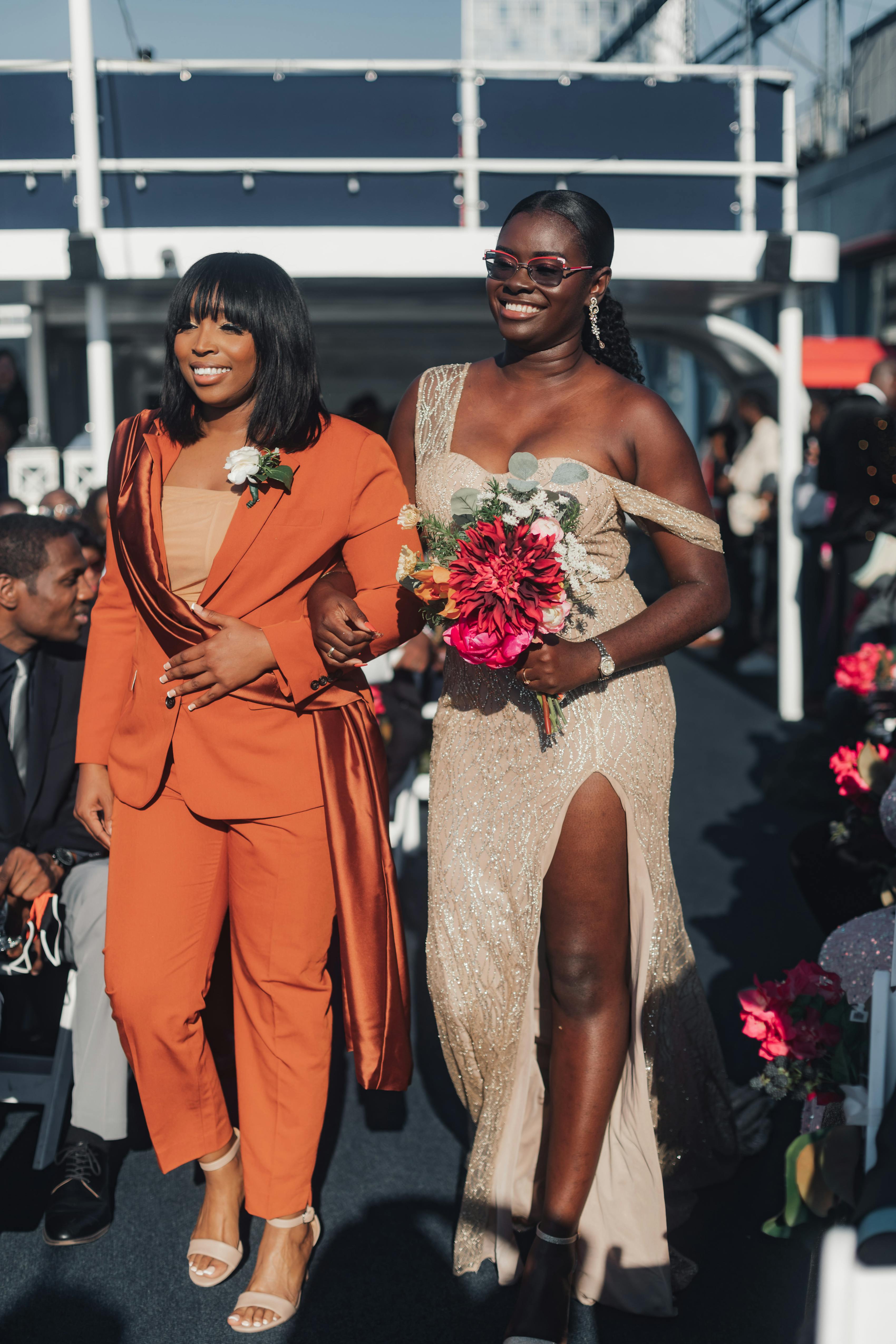 Bridesmaid walking down aisle wearing burnt orange women's suit