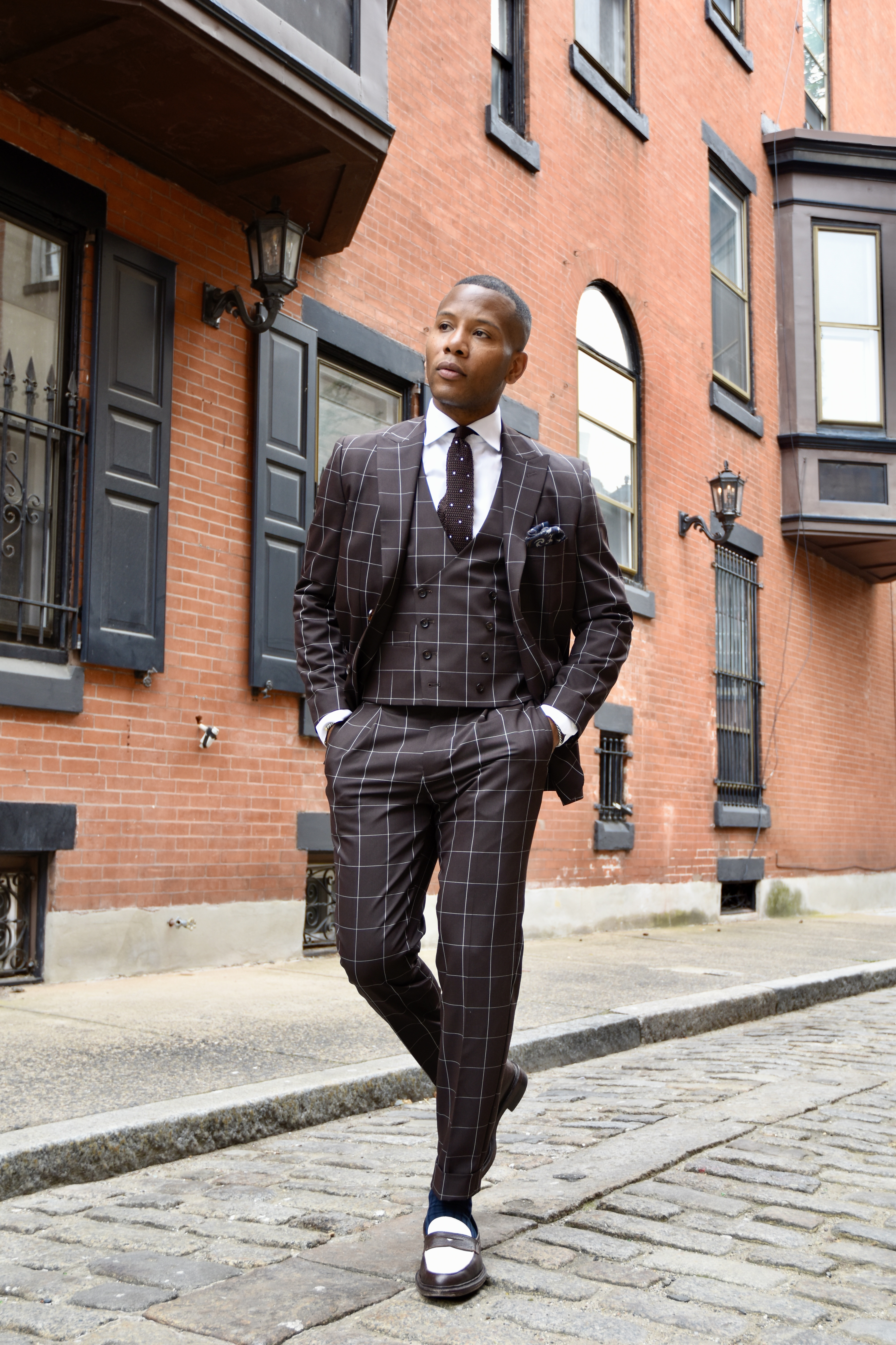 Fashionable man wearing chocolate brown windowpane suit set on city street