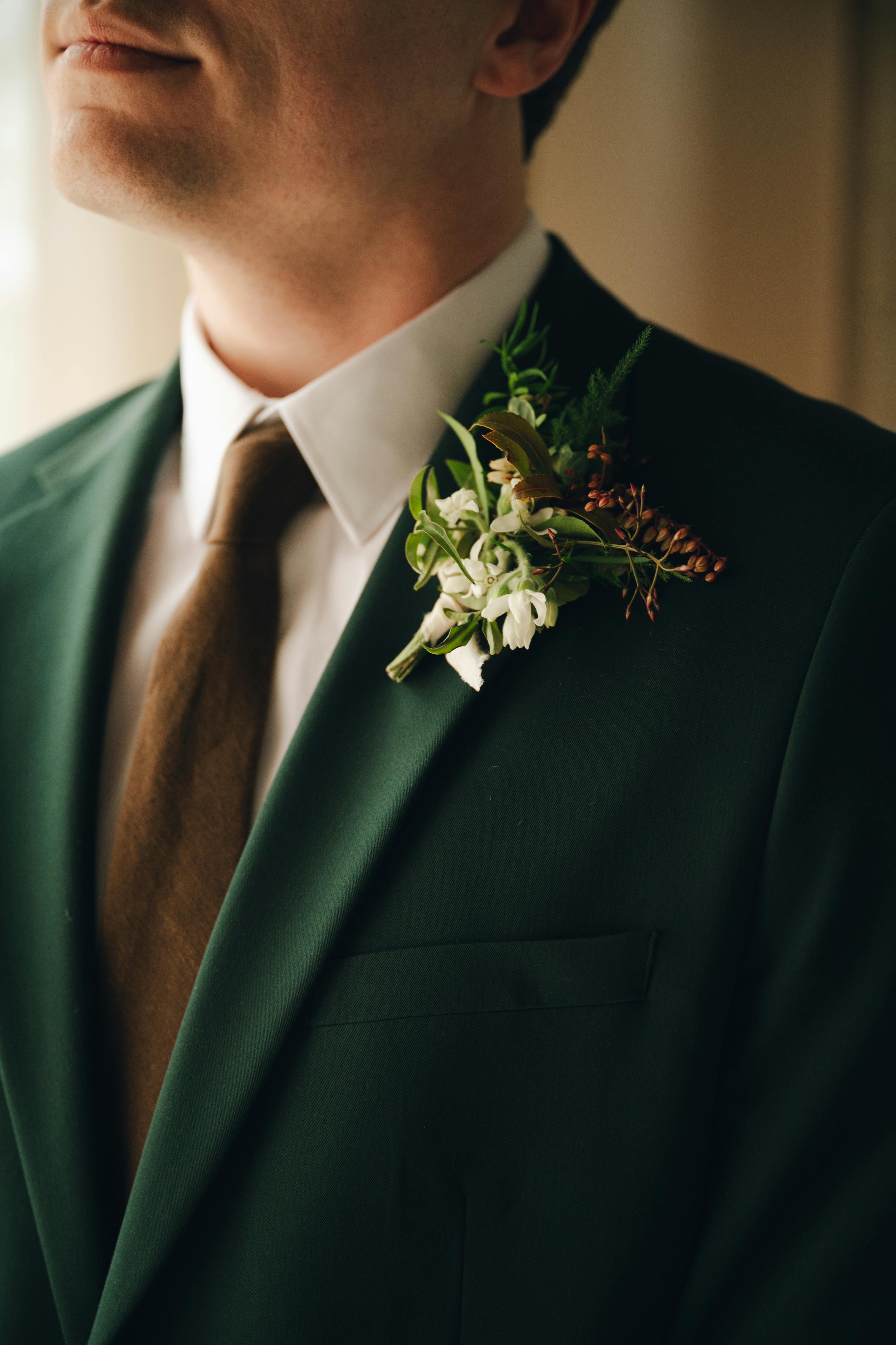 Groomsman wearing olive green suit with brown tie and boutonniere