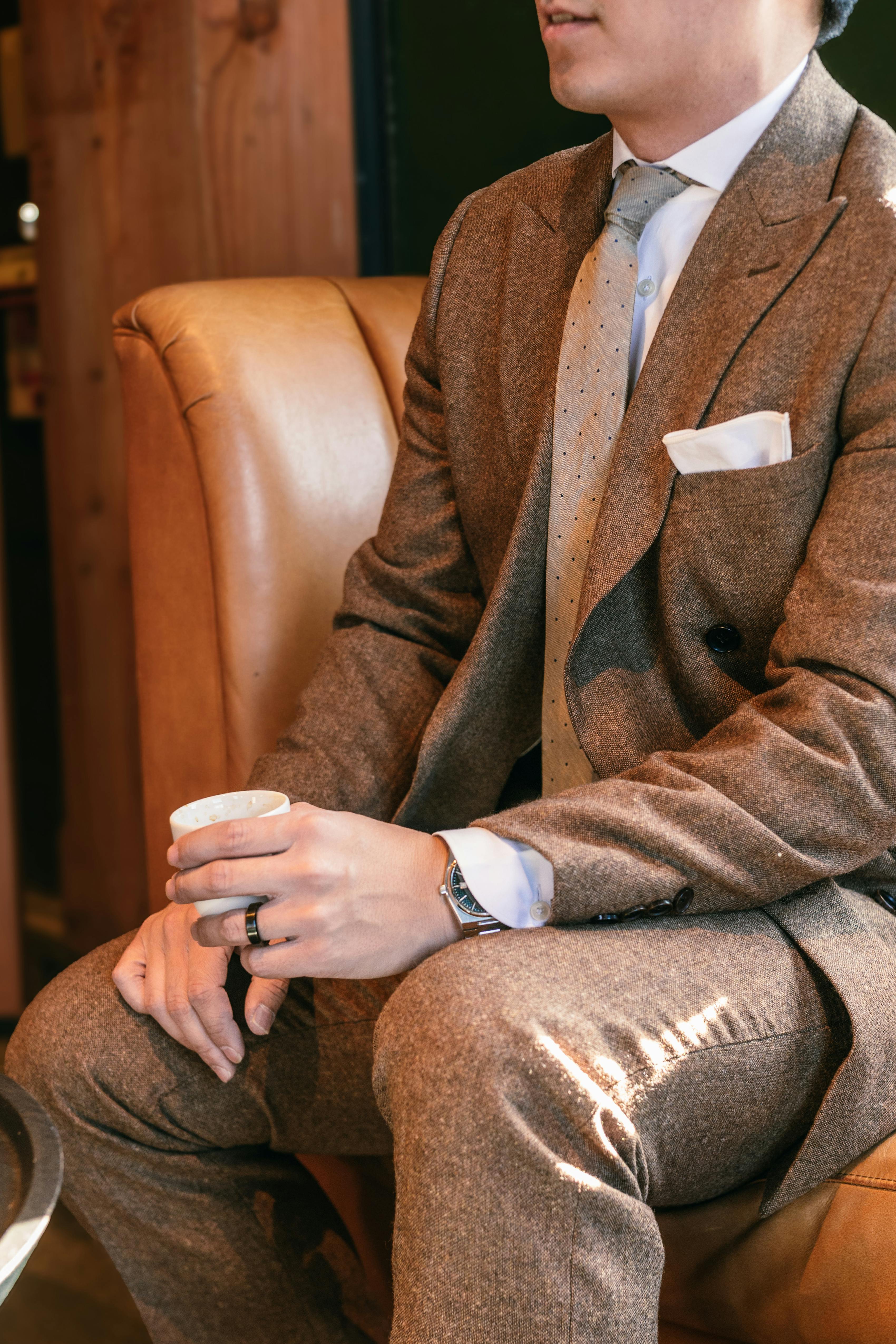 Brown tweed suit with white pocket square and patterned tie at wedding reception